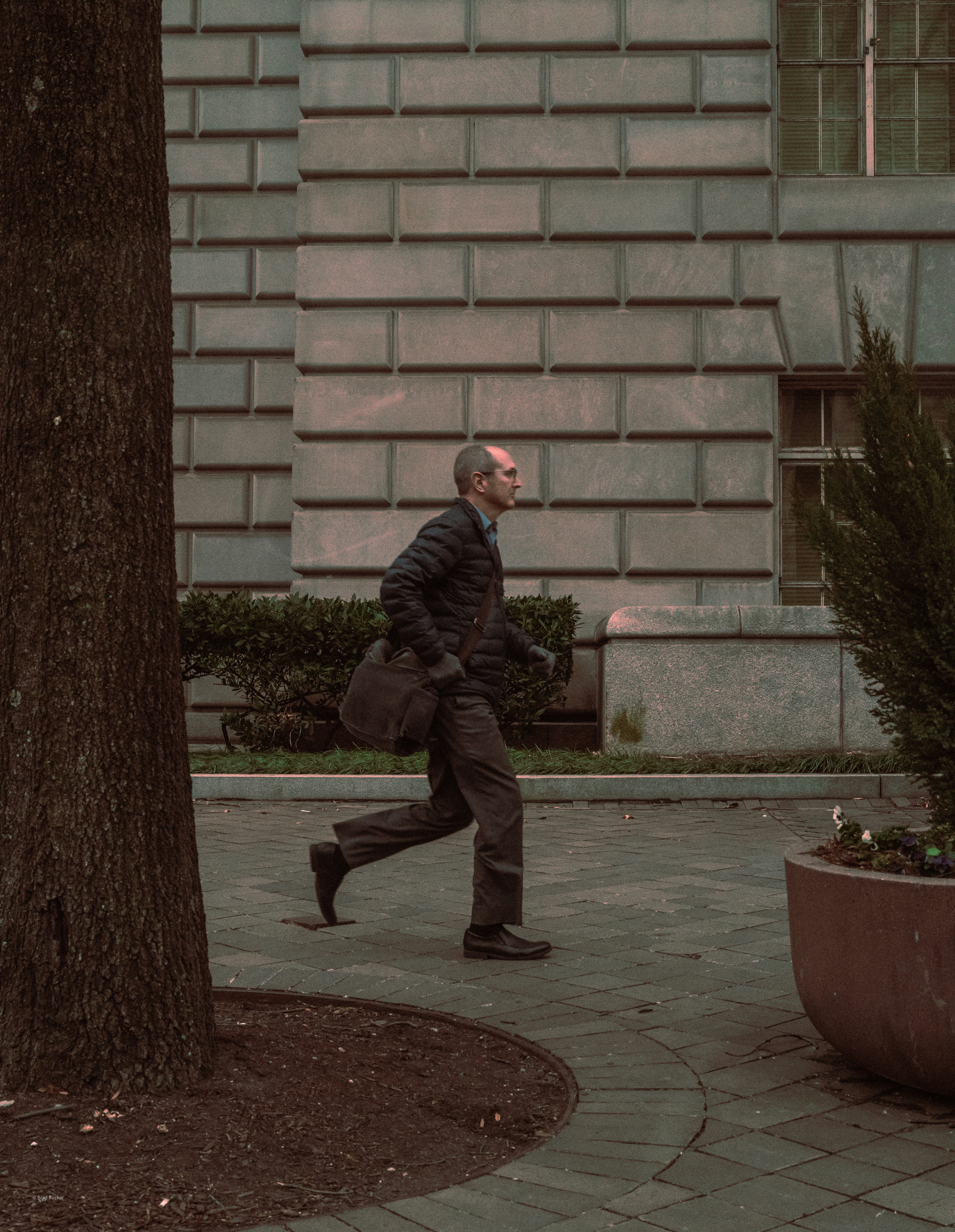 A man in a jacket runs past a building.