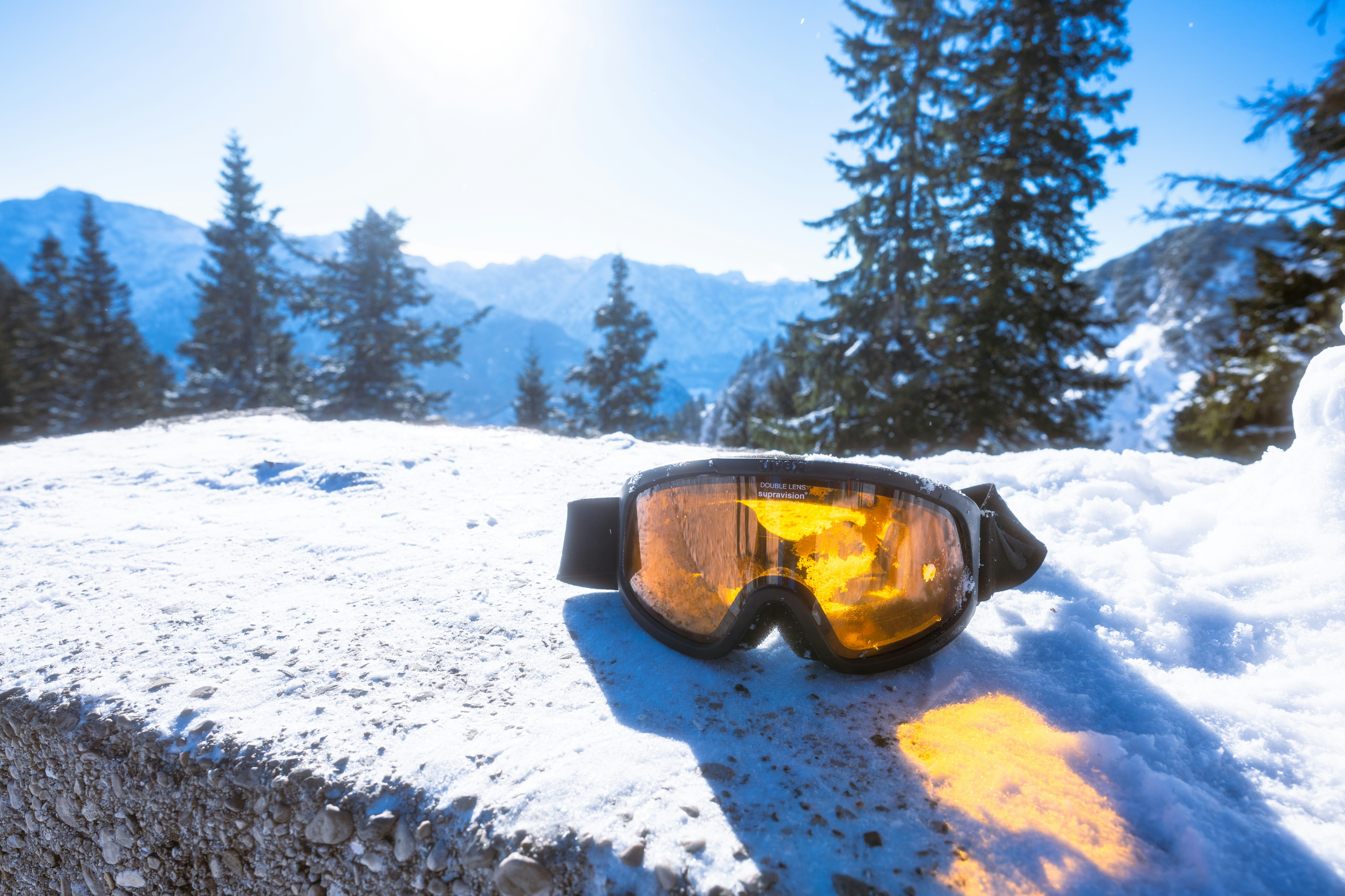 Gafas de esquí descansando sobre suelo nevado con montañas detrás