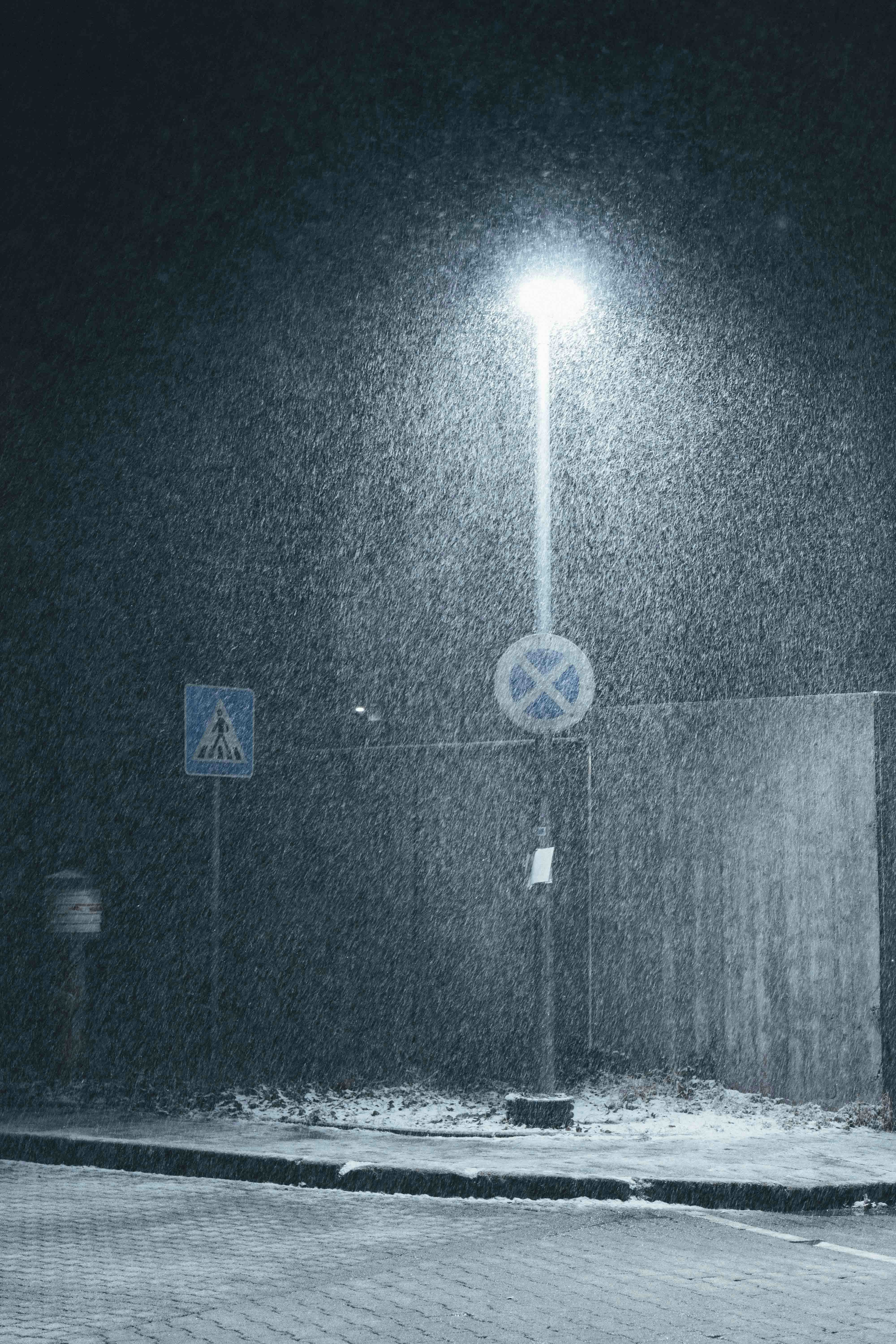 Streetlight illuminates falling snow at night.
