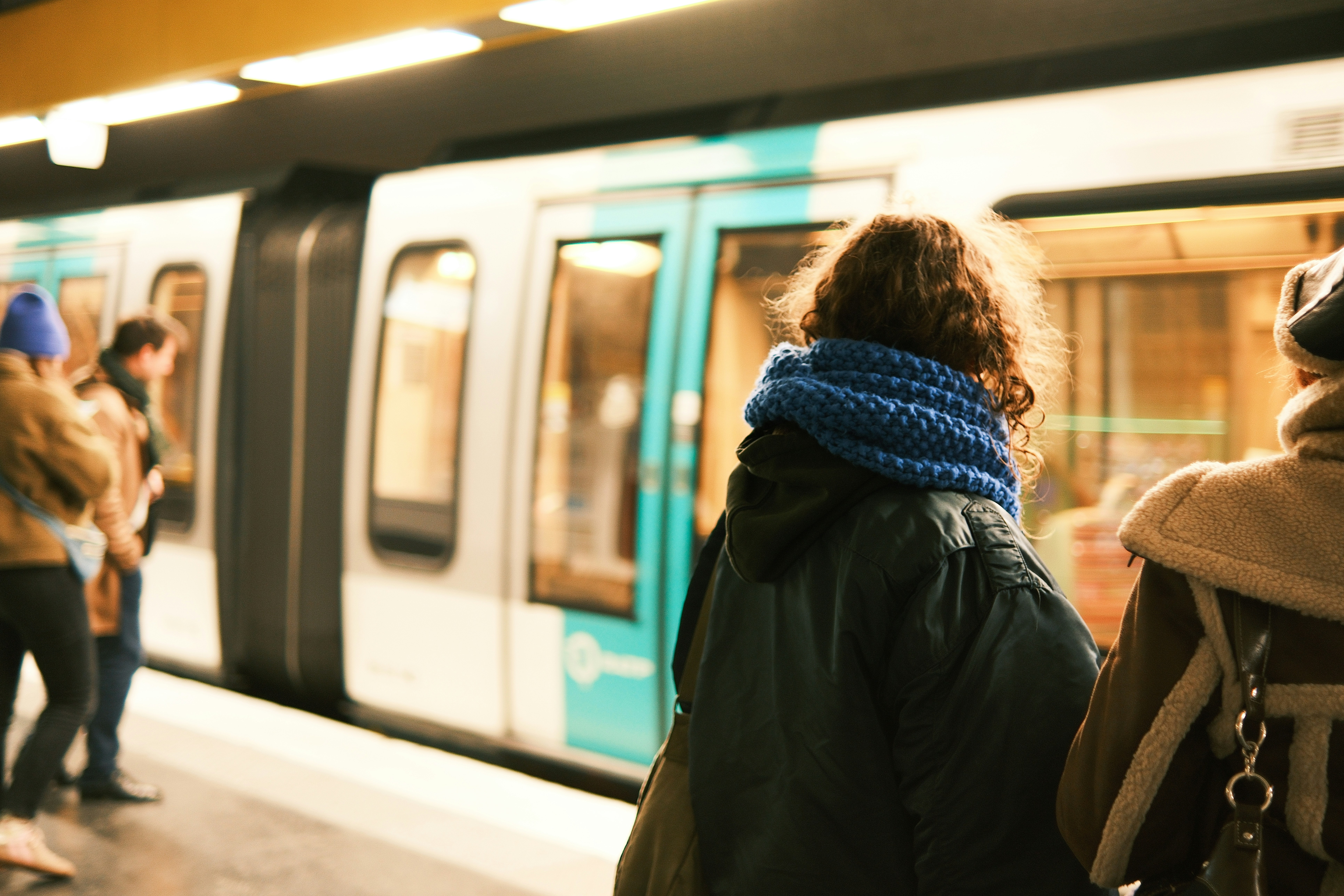 People wait for a train on a subway platform.