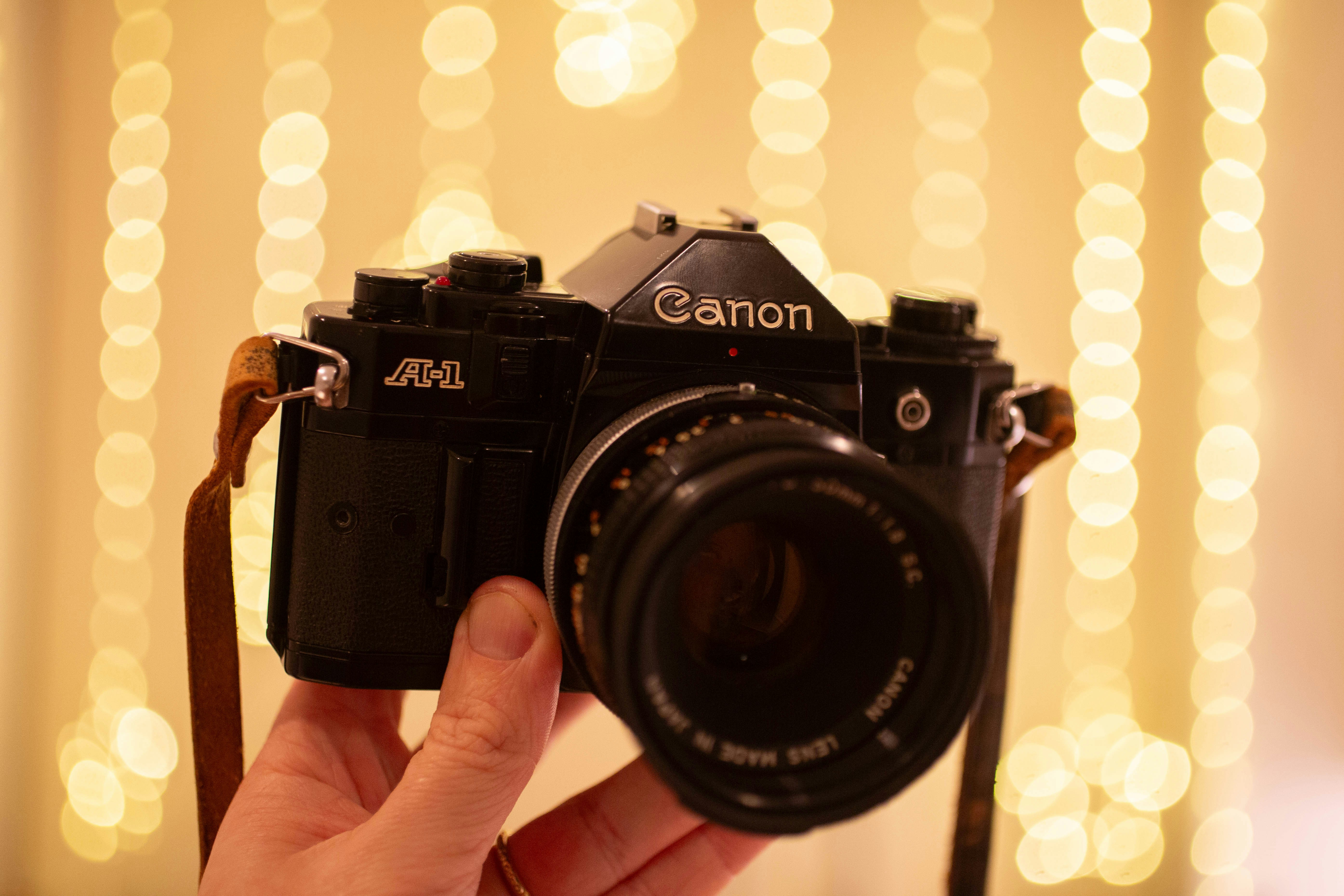 A black canon slr camera held in hand