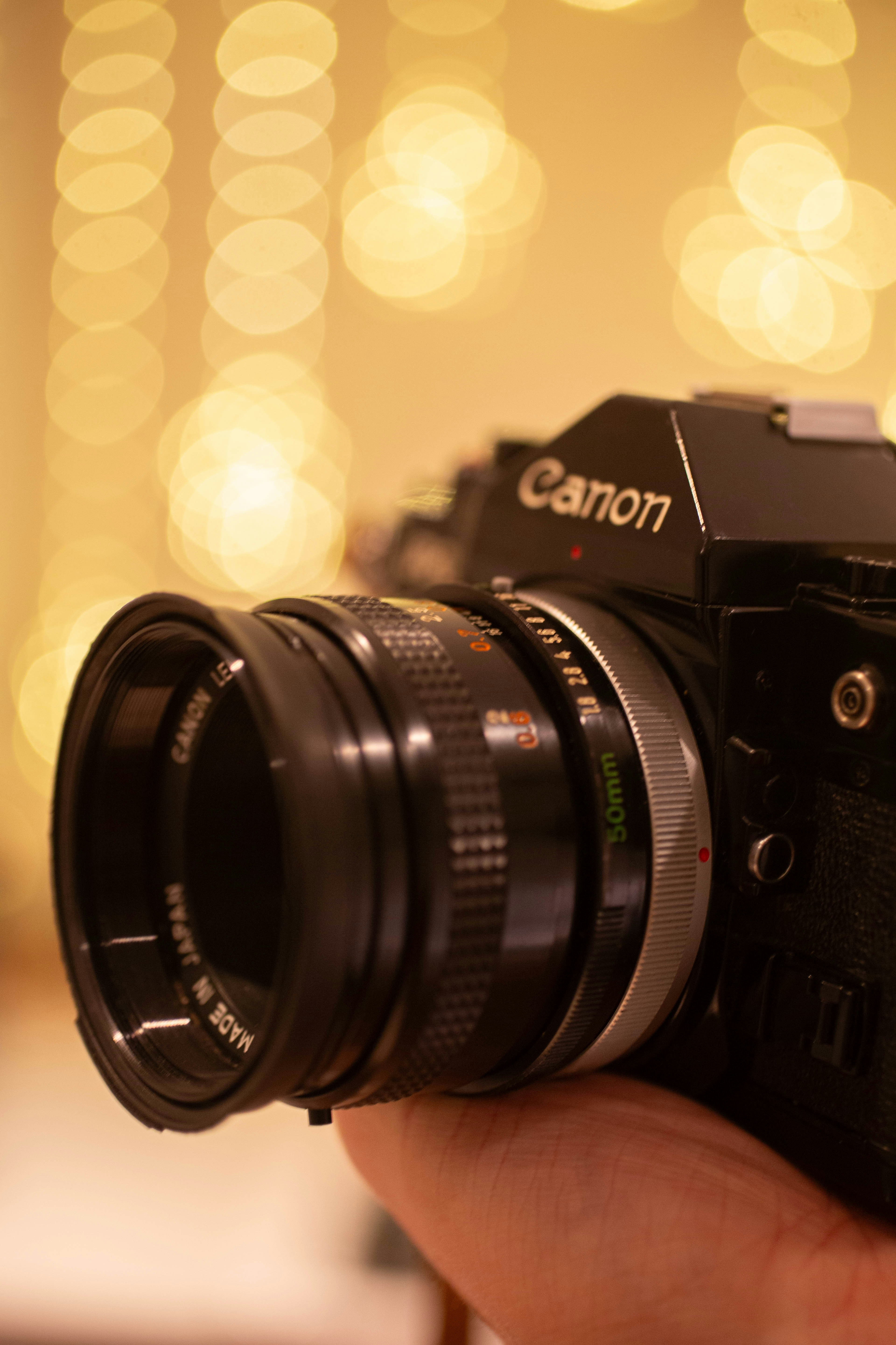 Close-up of a vintage canon camera with bokeh lights.