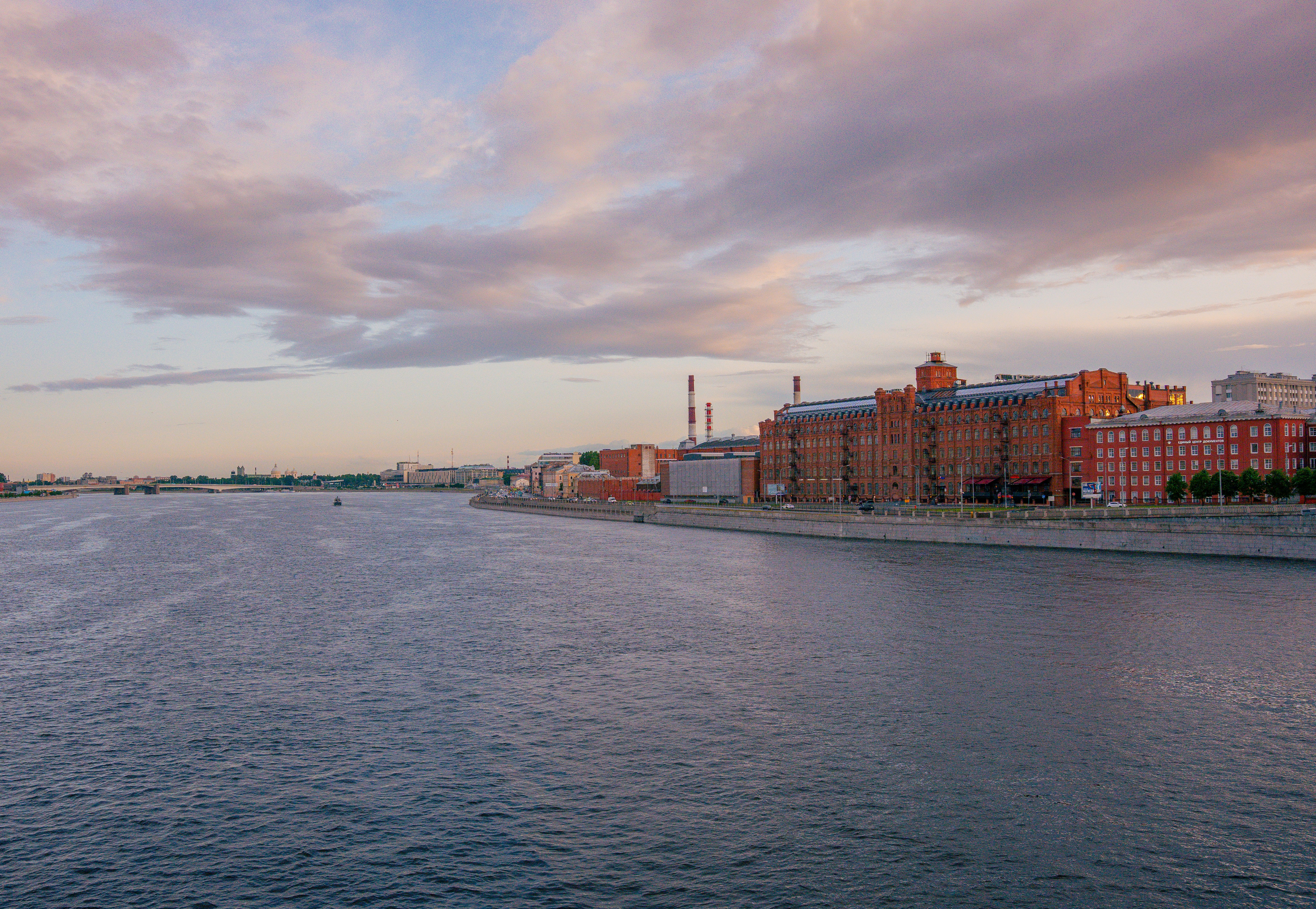 River flowing past brick buildings under a cloudy sky