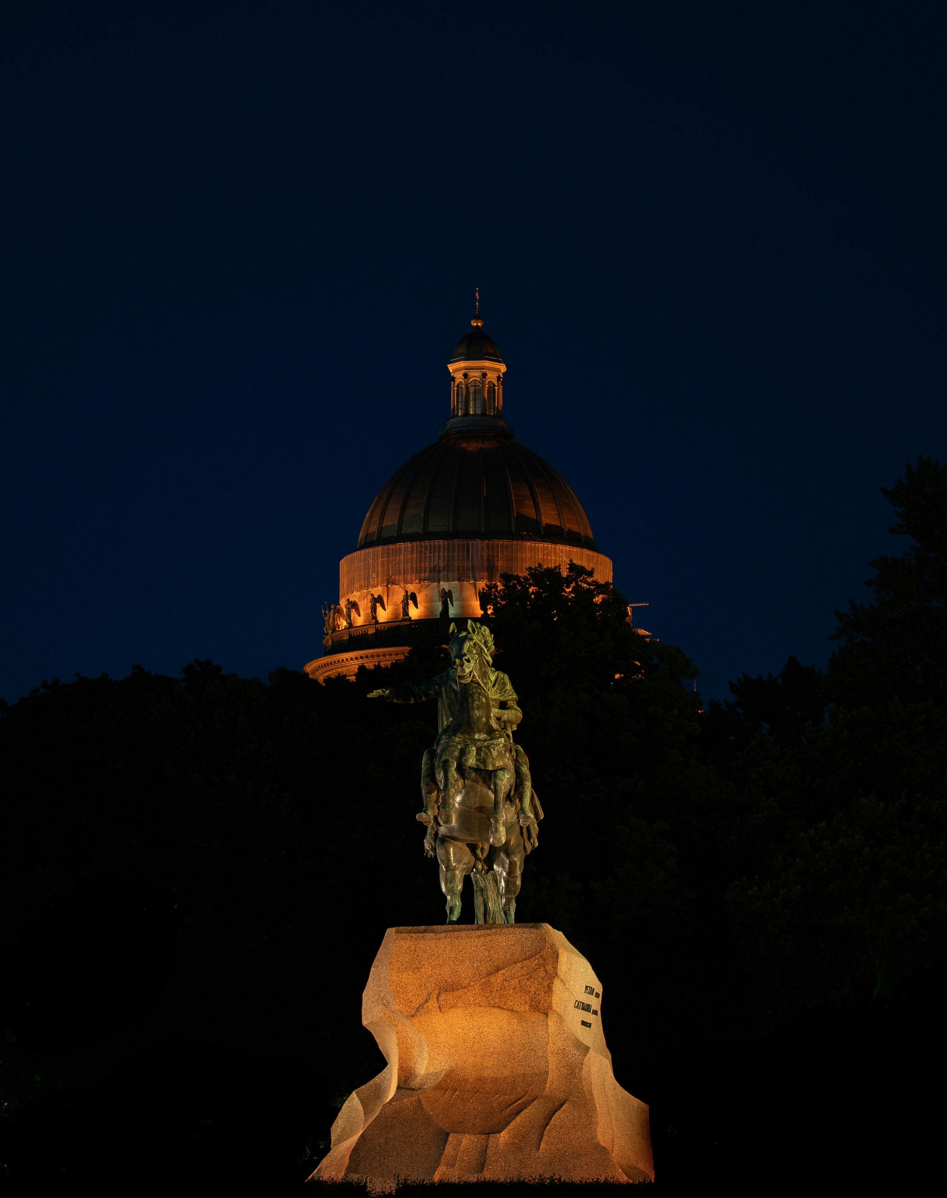 Equestrian statue with illuminated dome at night
