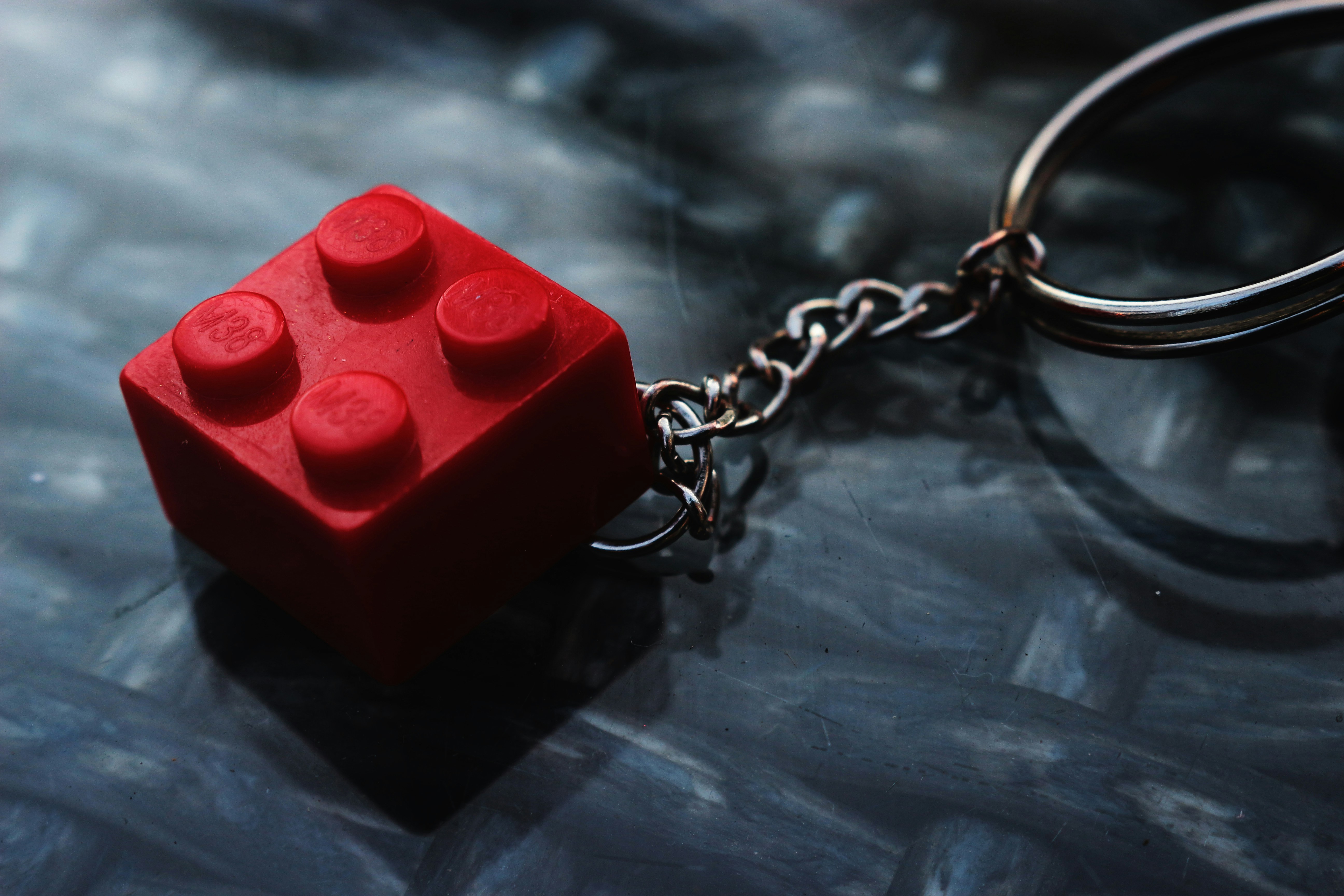 Red building block keychain on a textured surface.