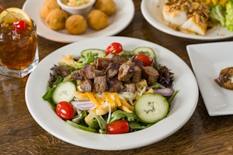 A steak salad with cherry tomatoes and cucumber slices.