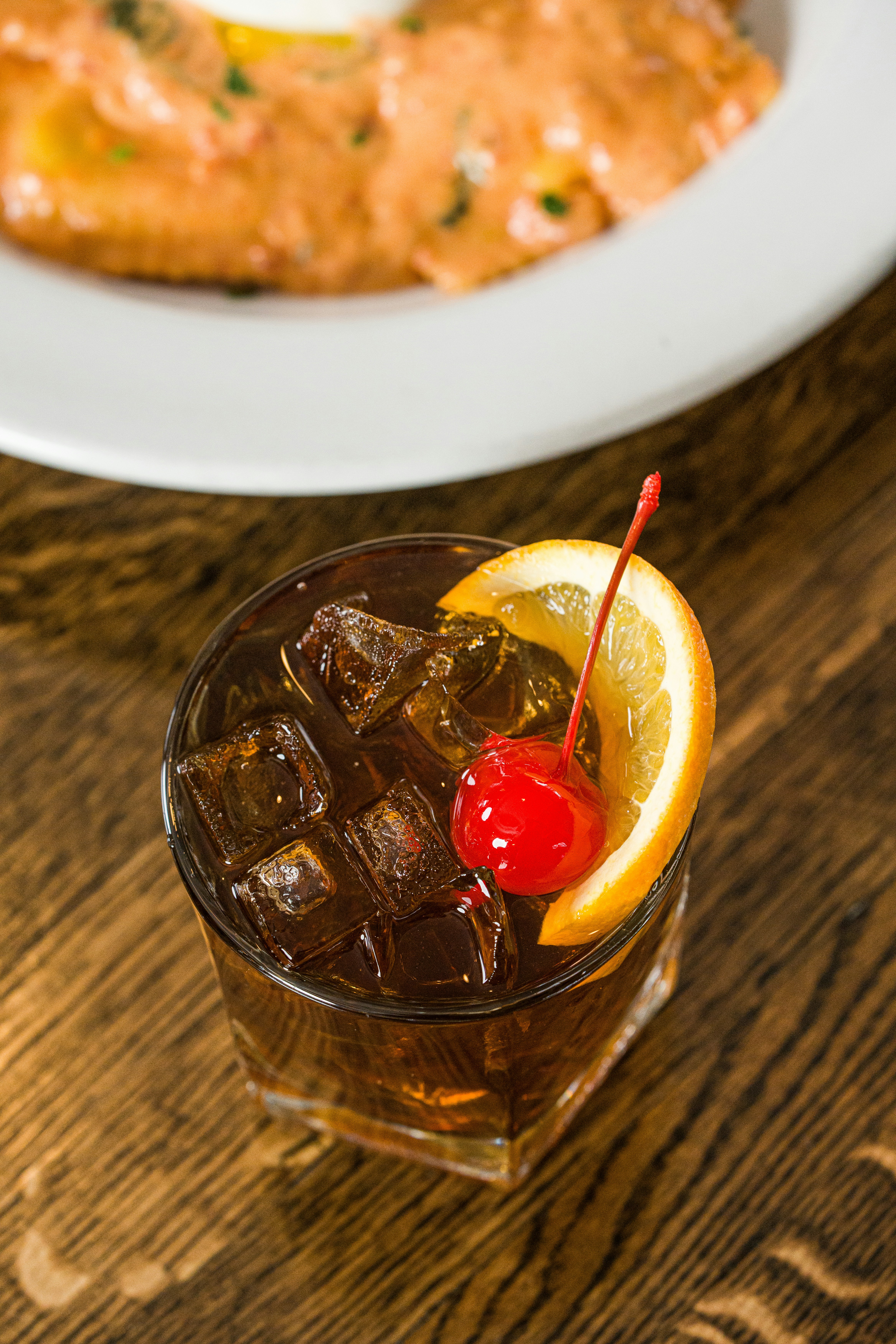 Old fashioned cocktail with orange slice and cherry