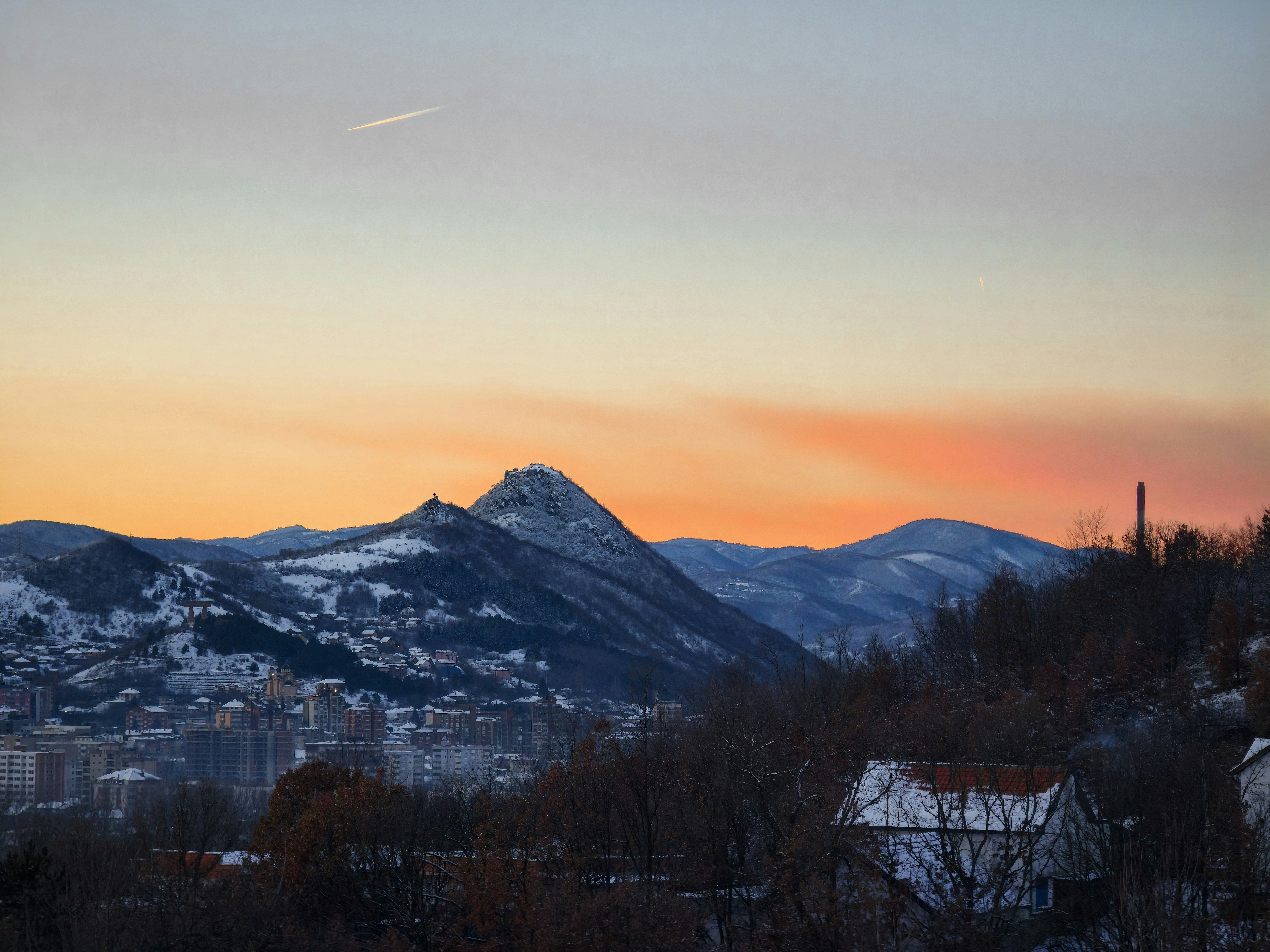 Snowy mountains at sunset with a small town below
