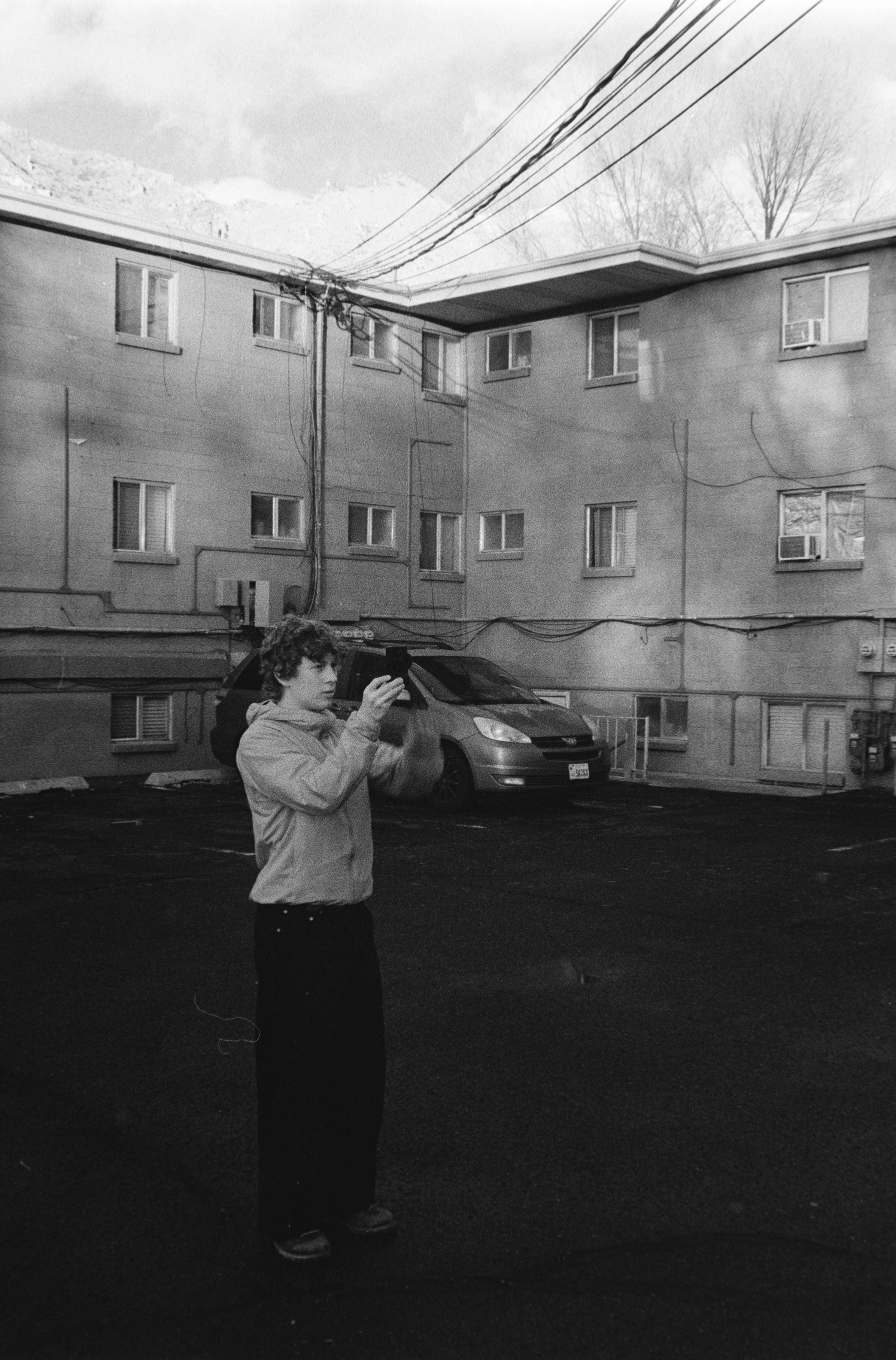 Young man holding a phone in a parking lot.