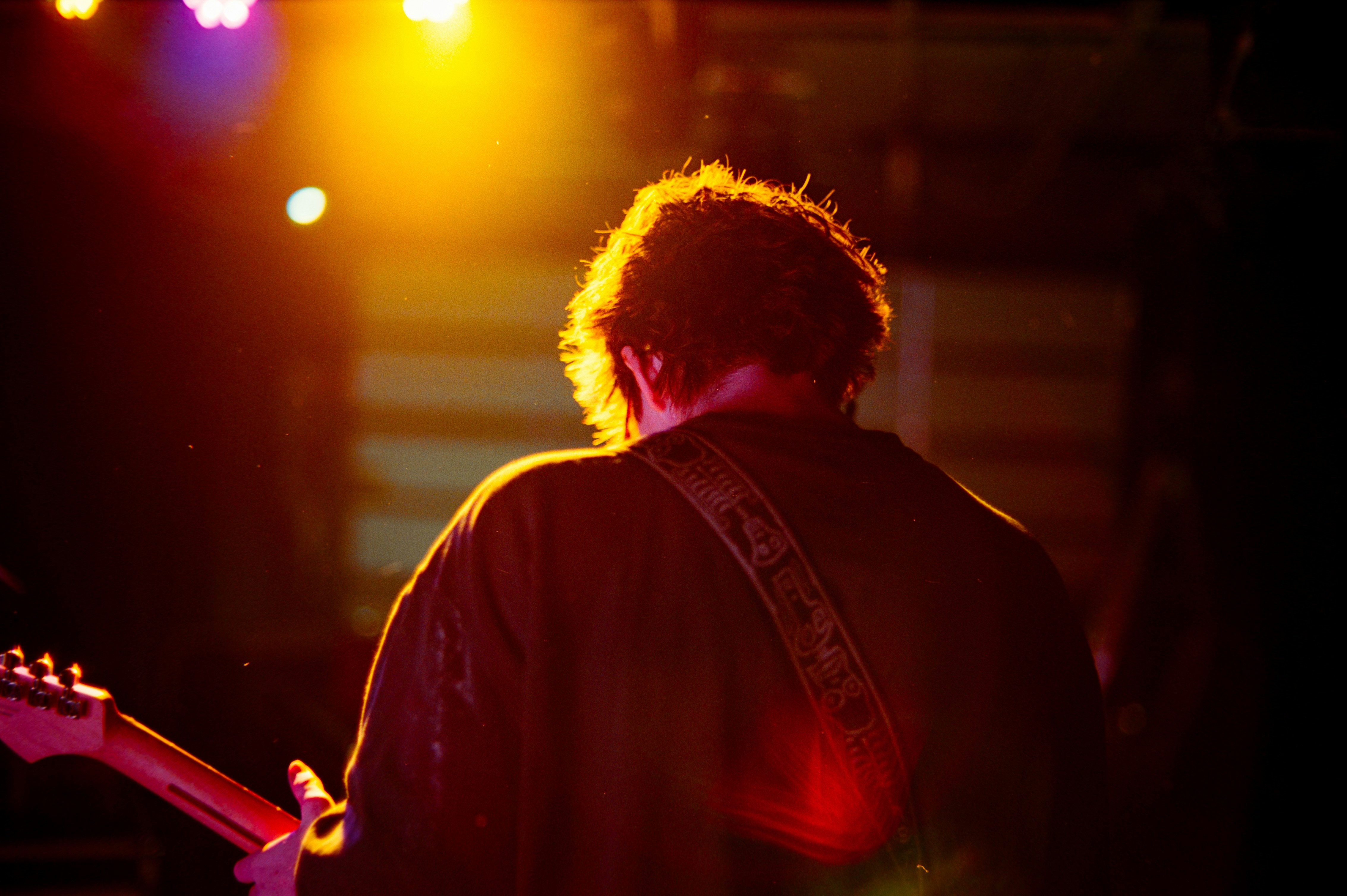 Musician playing guitar on a dimly lit stage.
