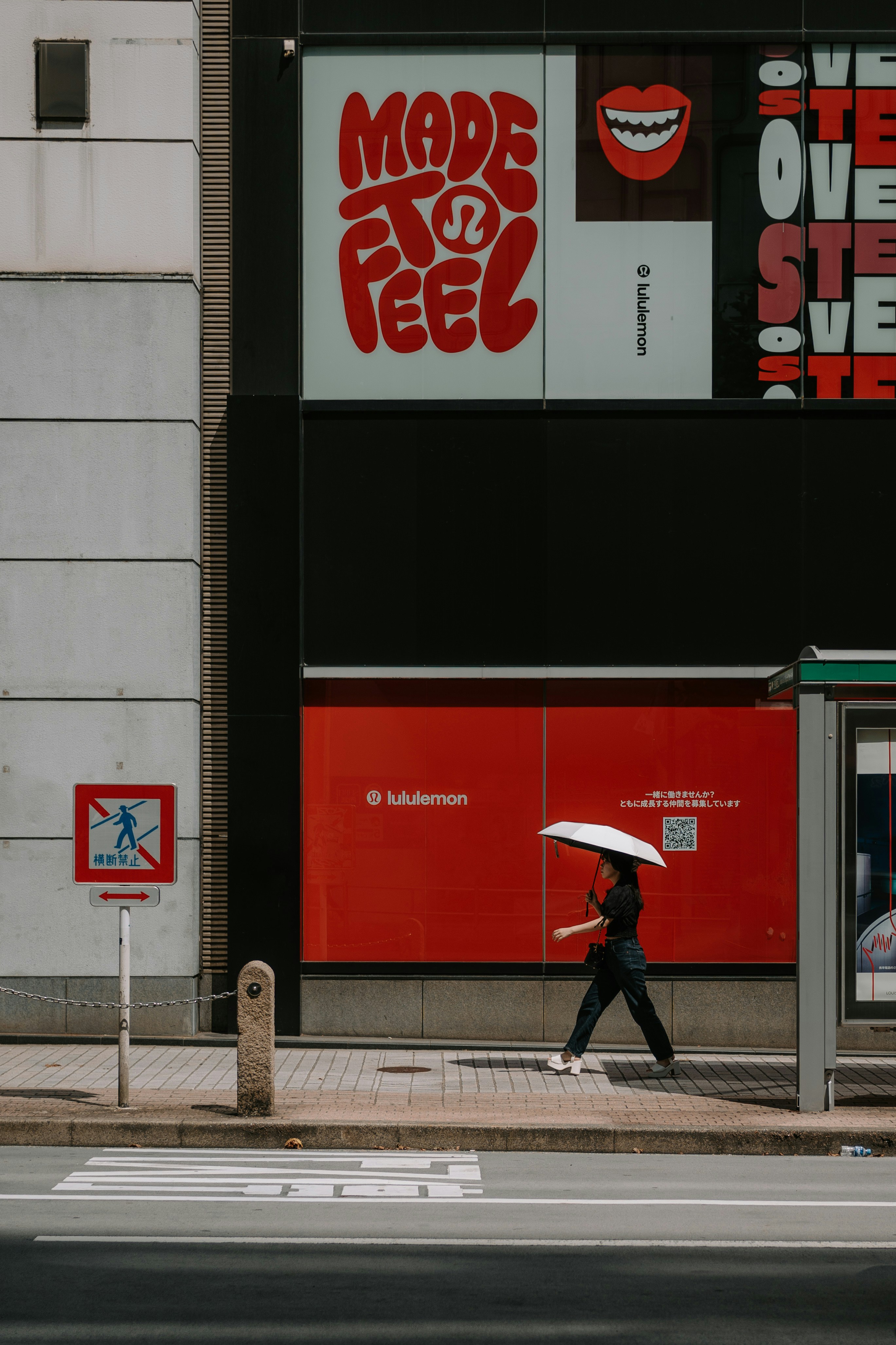 Woman with umbrella walks past lululemon store