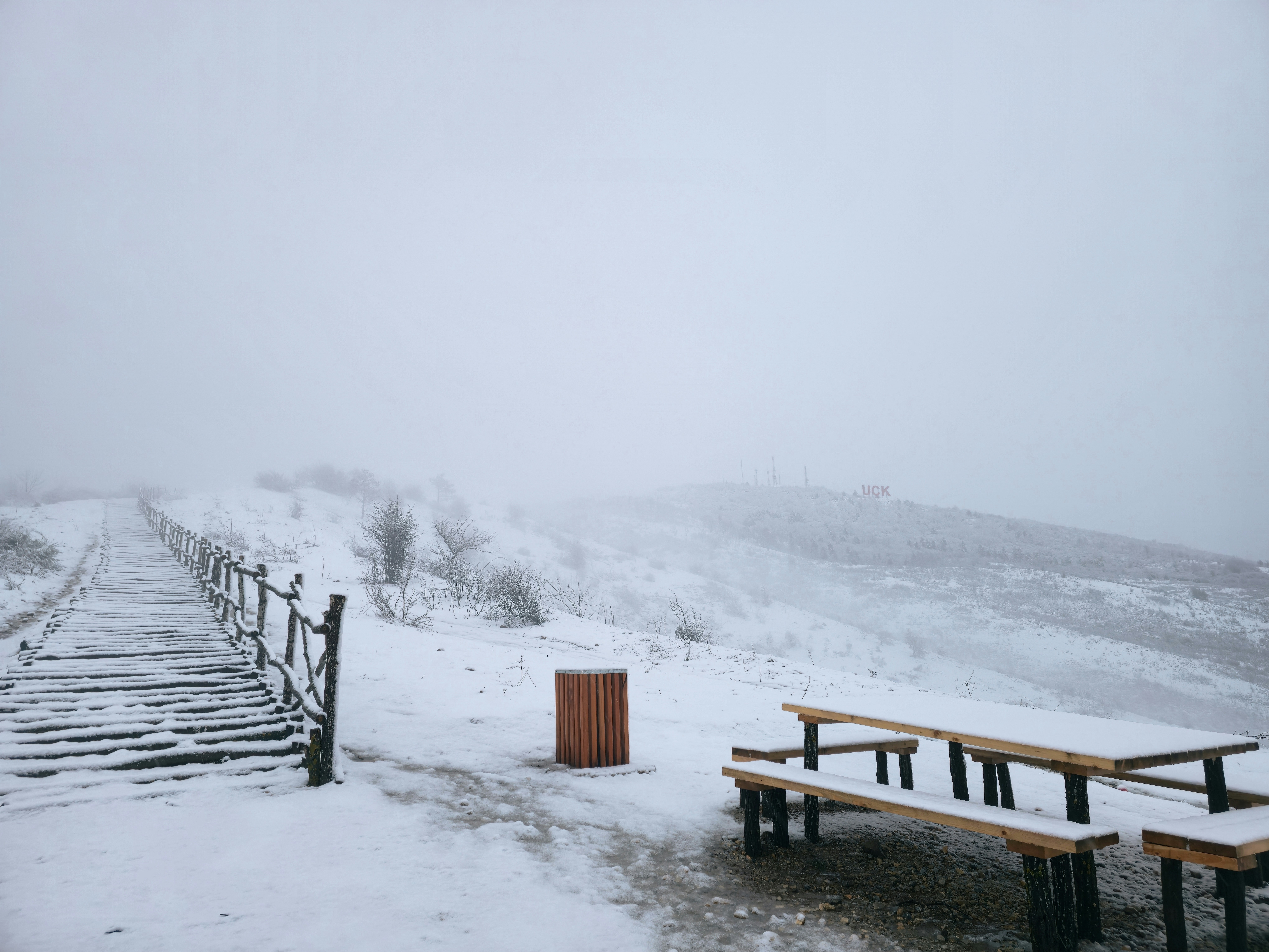 Snowy path with wooden benches and trash can