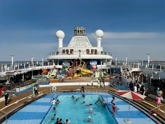 People swimming in a pool on a cruise ship deck.