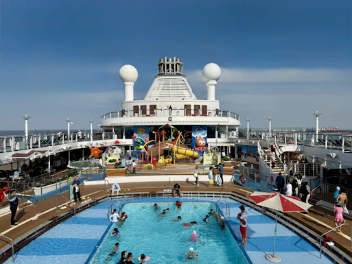 People swimming in a pool on a cruise ship deck.