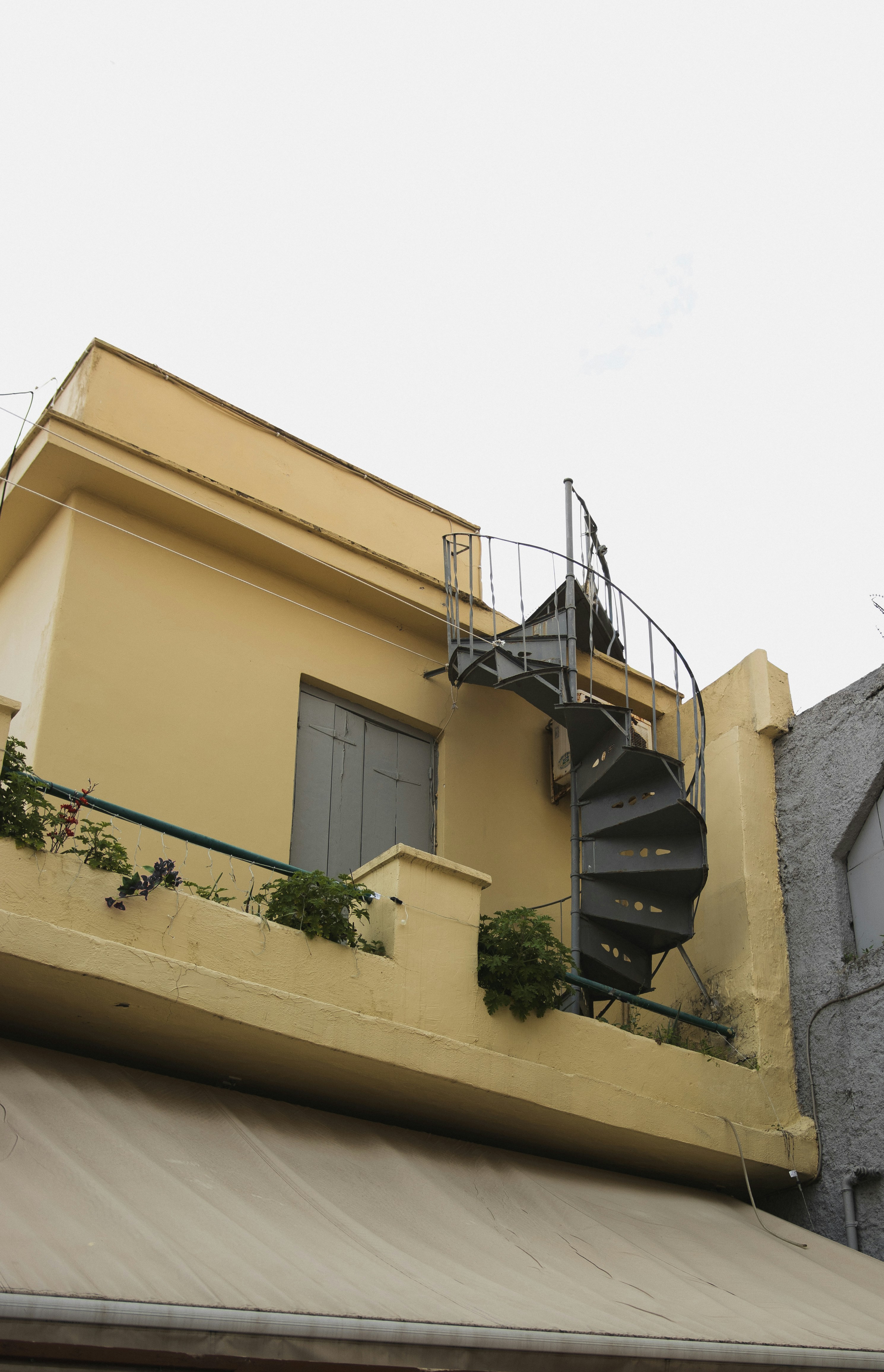 A yellow building with a spiral staircase outside.
