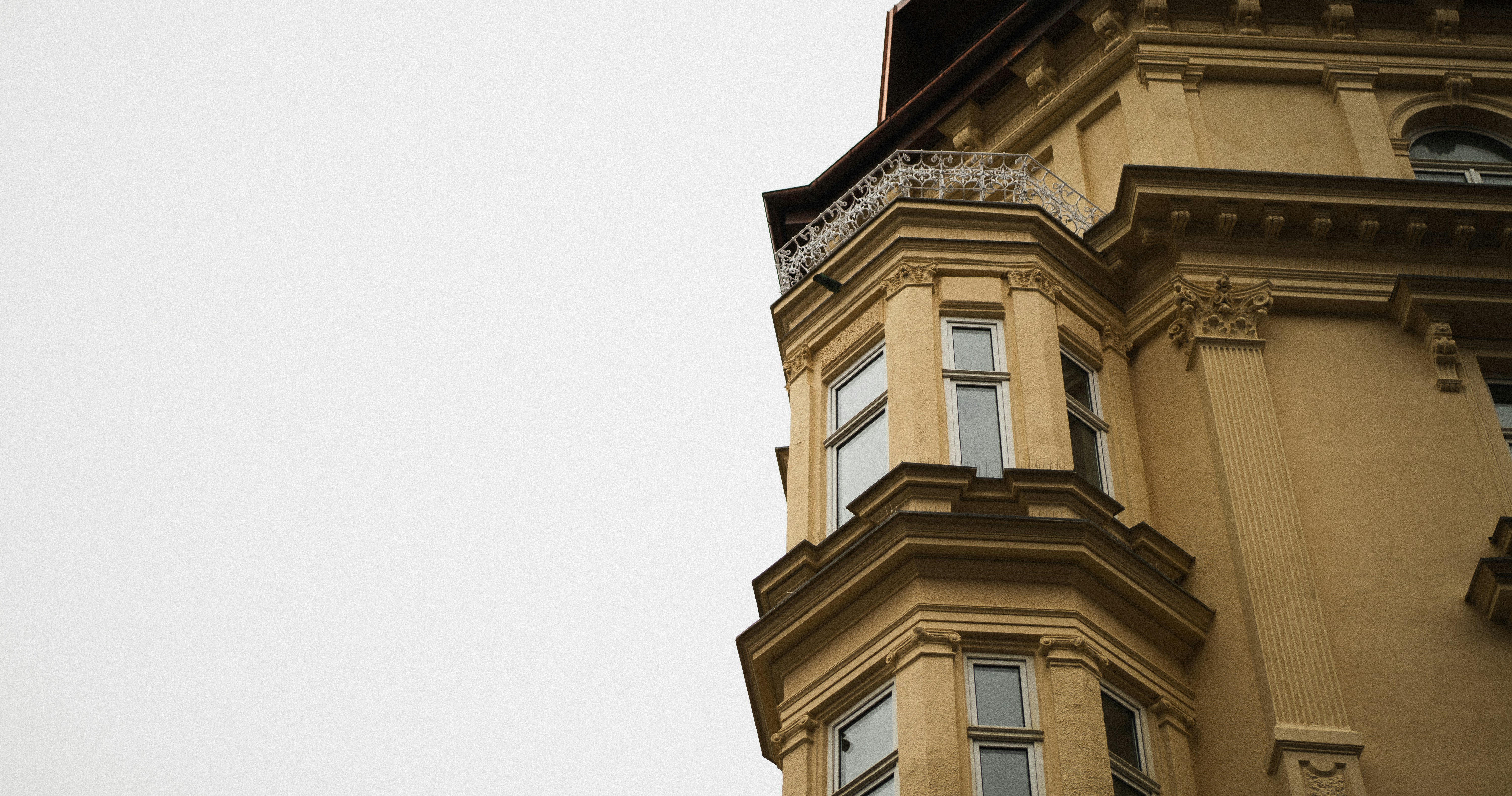 Corner of an old yellow building against a pale sky