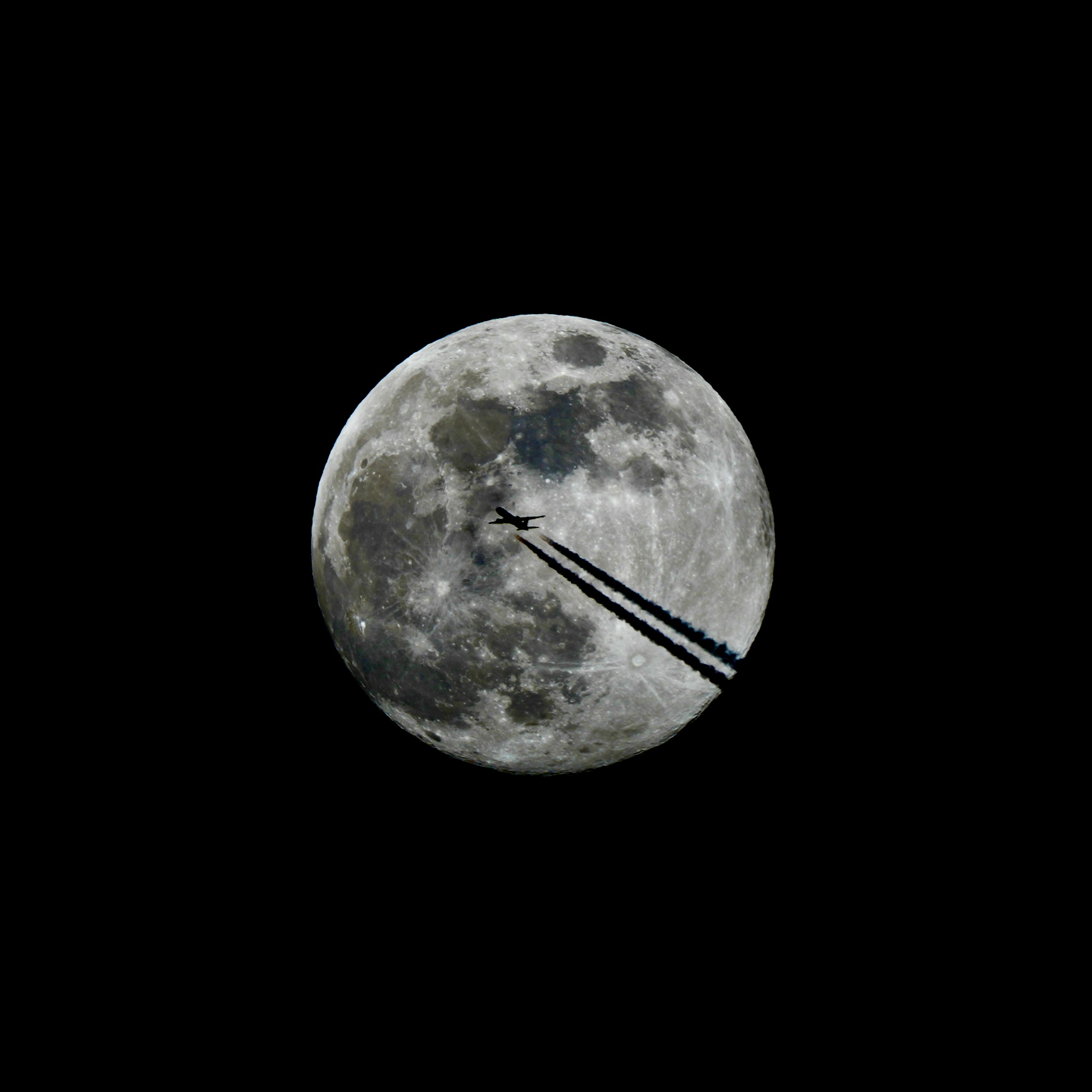 Airplane flying across the full moon