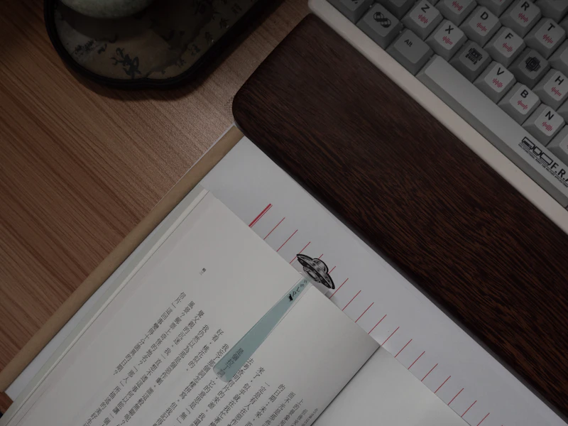 An open book with a bookmark next to a keyboard