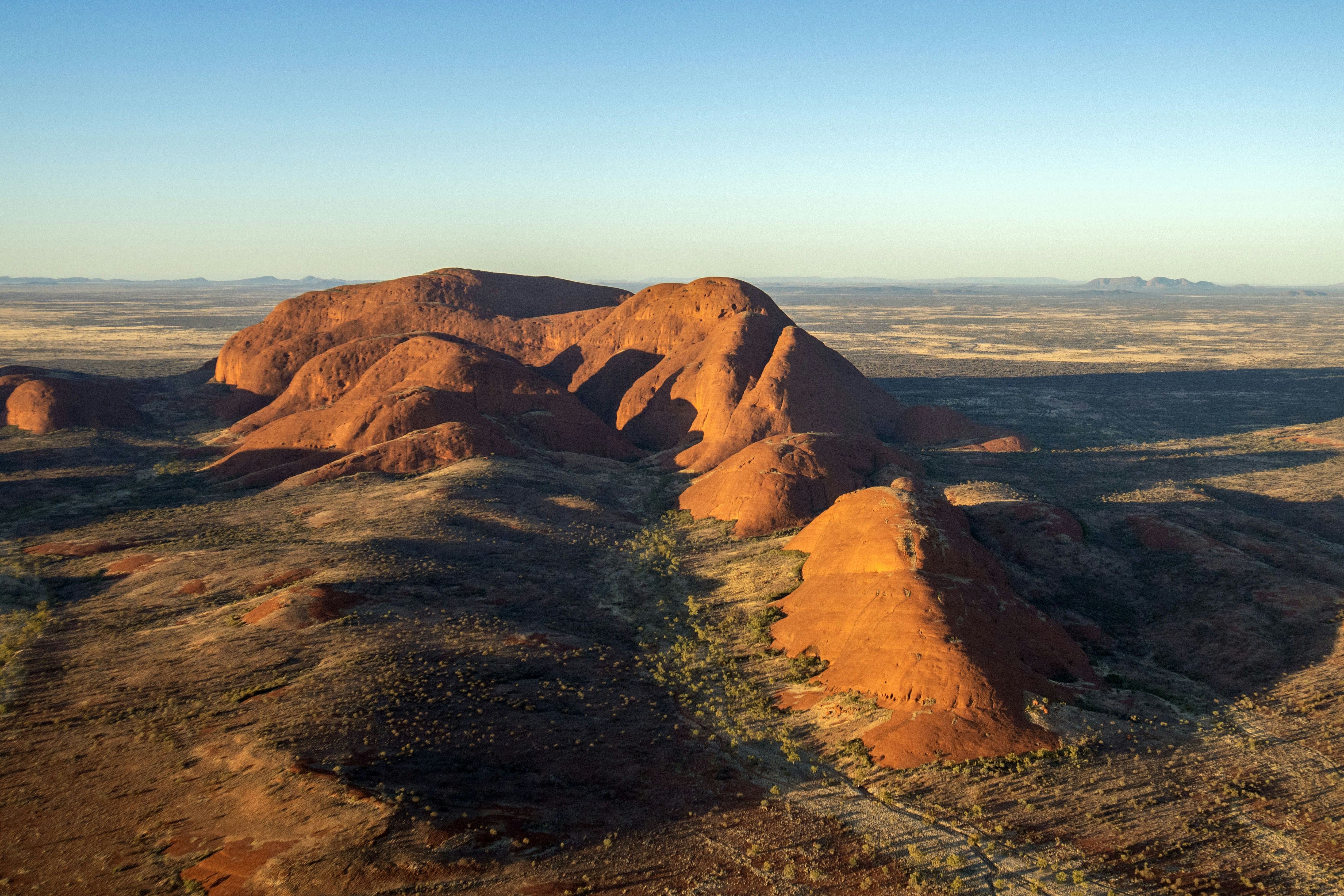 Red desert landscape with large rock formations at sunrise.