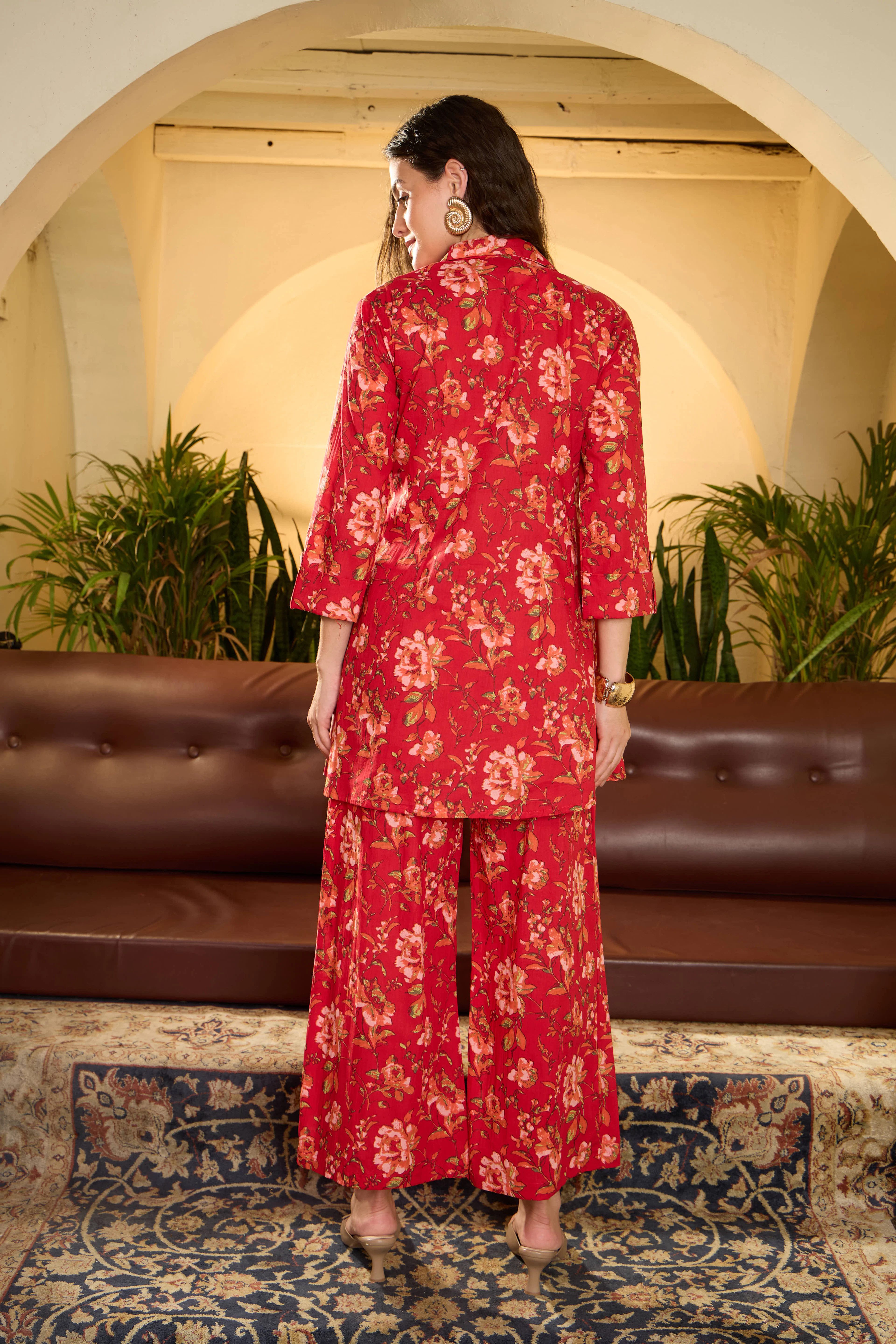 Woman in a scarlet floral suit set standing indoors