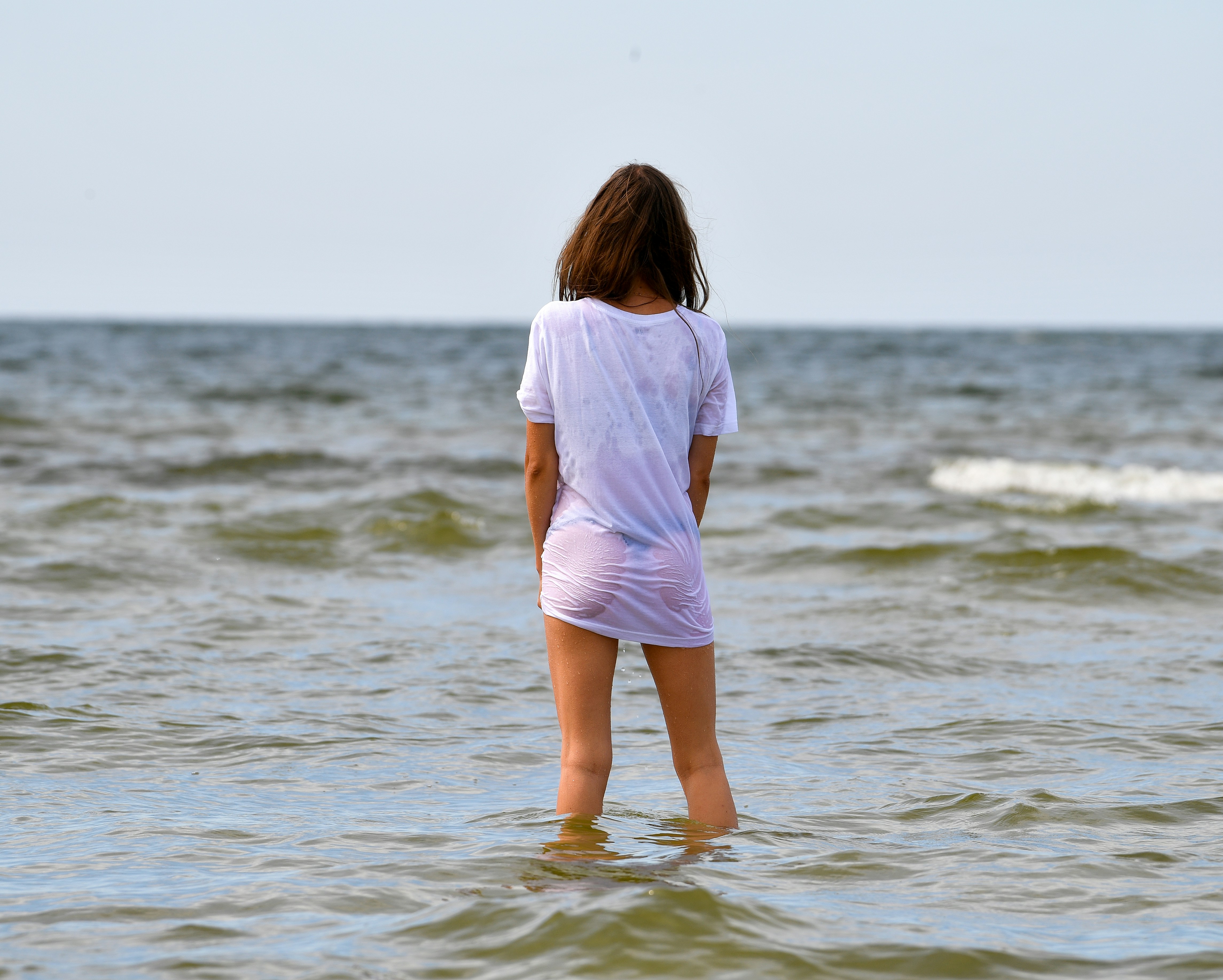Woman in wet t-shirt standing in the ocean