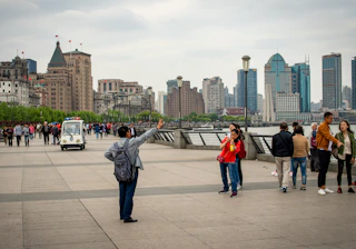 People taking photos along a waterfront with city skyline.