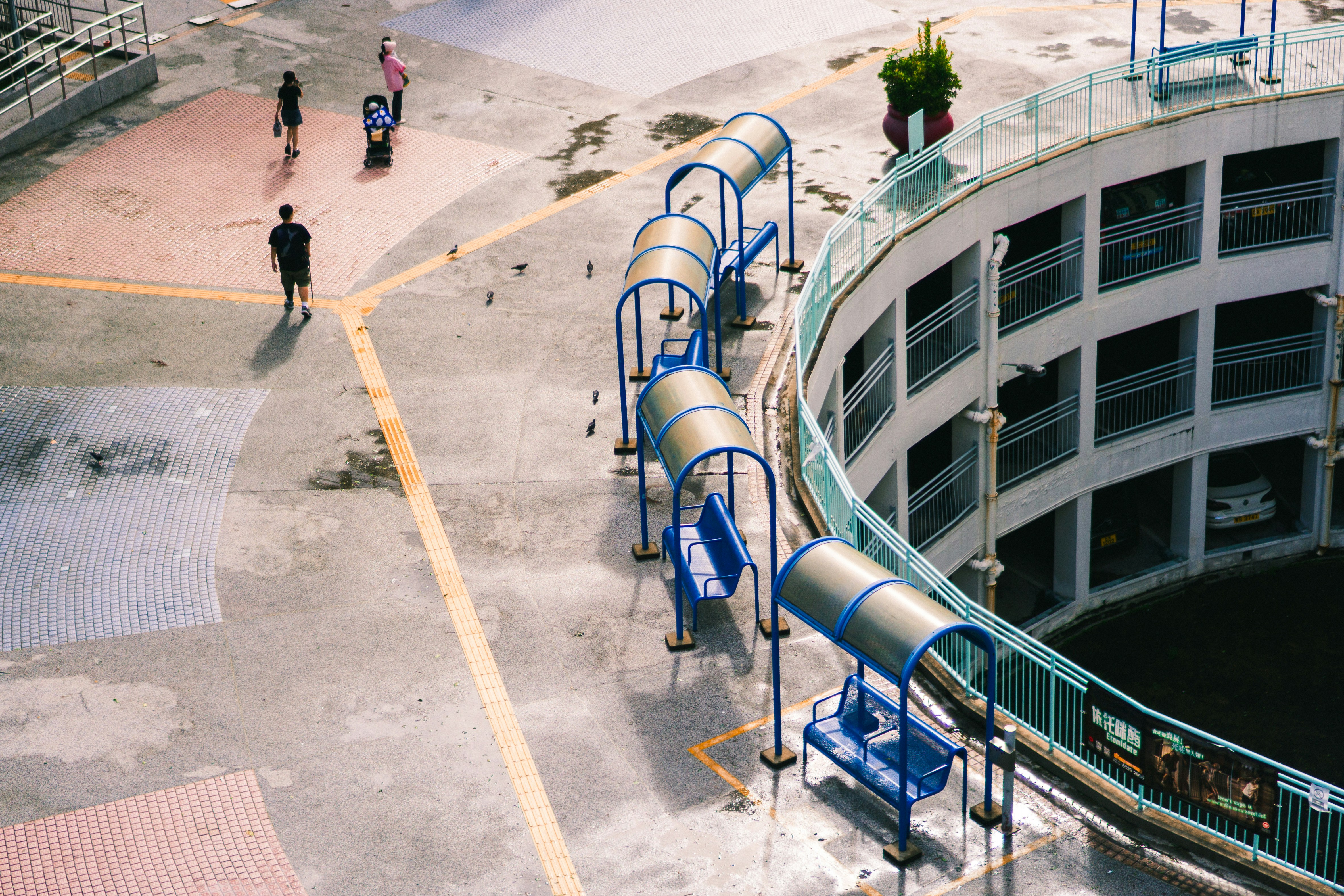 Menschen, die auf einem nassen, draußen gehischen Weg mit blauen Unterständen spazieren.