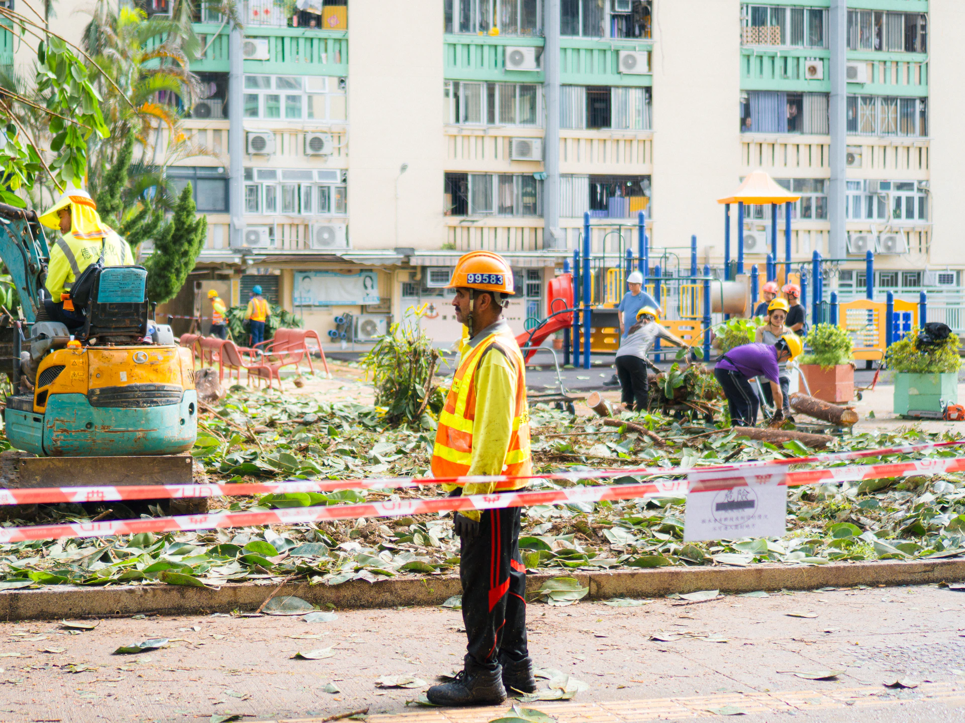 Workers clean up debris after storm damage in a park.