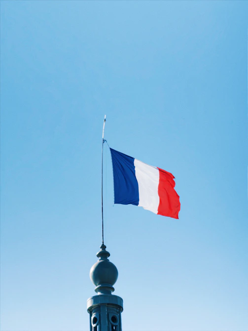 The french flag waves against a clear blue sky.