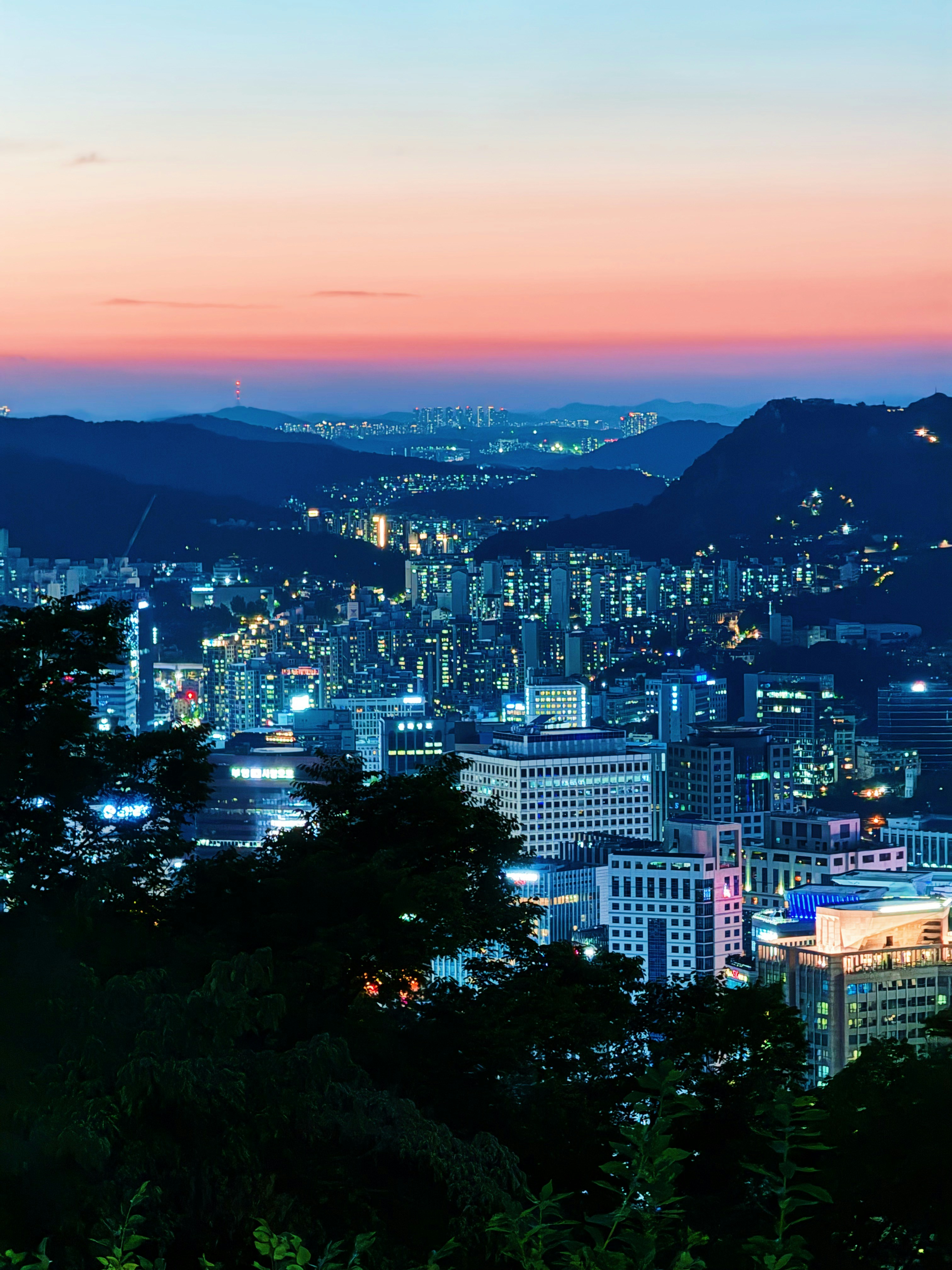 Cityscape at dusk with glowing lights and colorful sky
