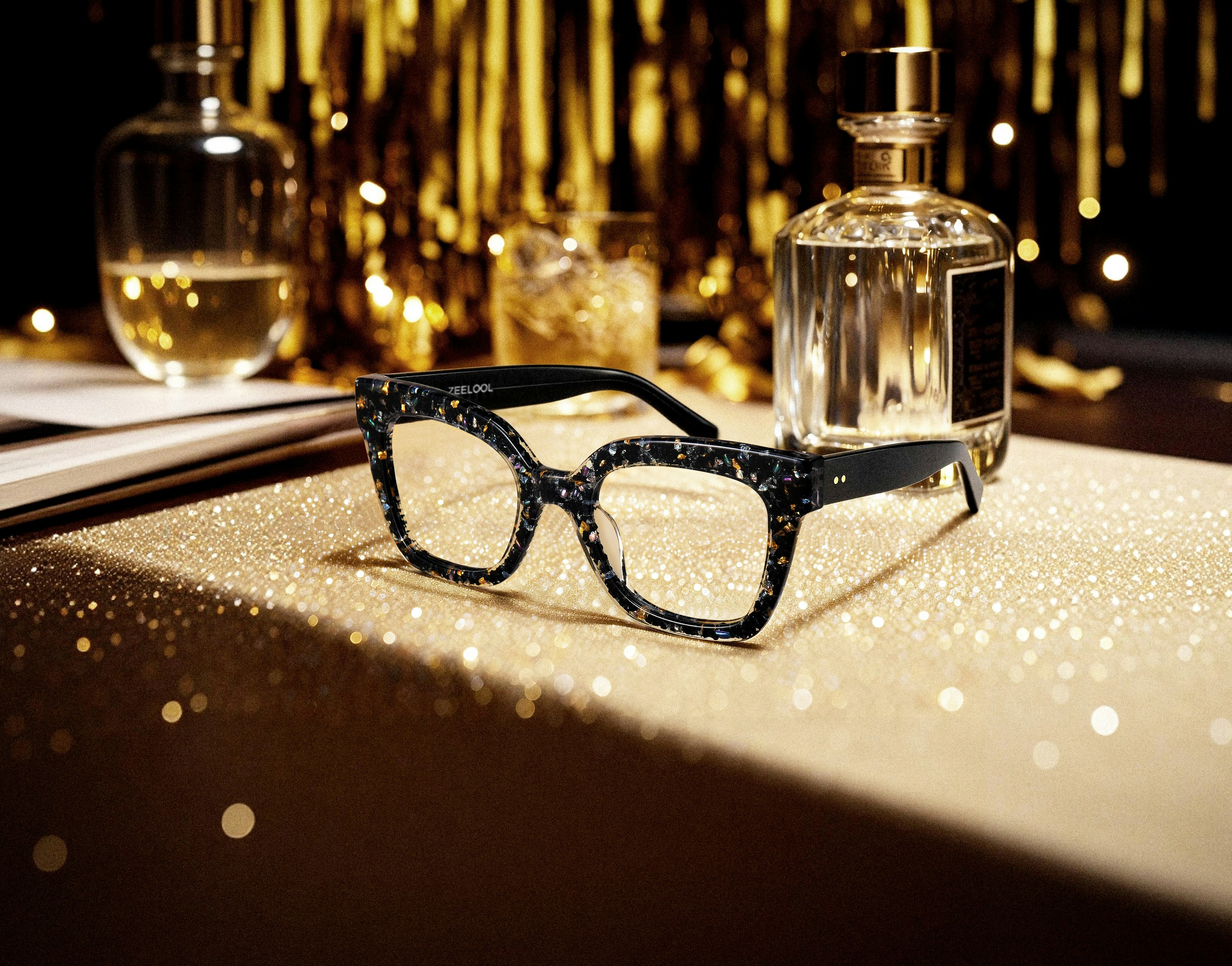 Stylish glasses on a sparkling gold surface with bottles.
