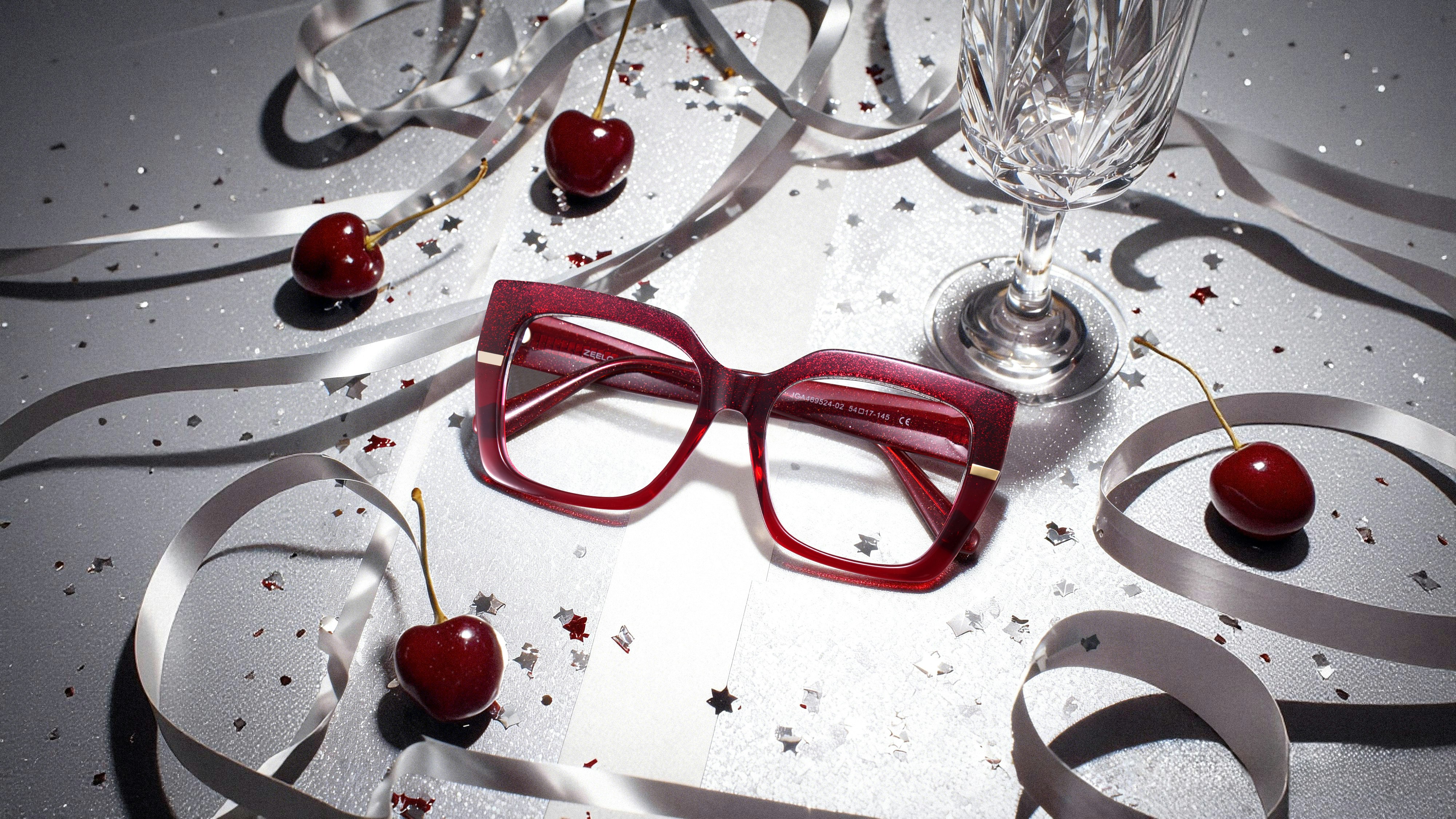 Red eyeglasses with cherries and confetti on a table