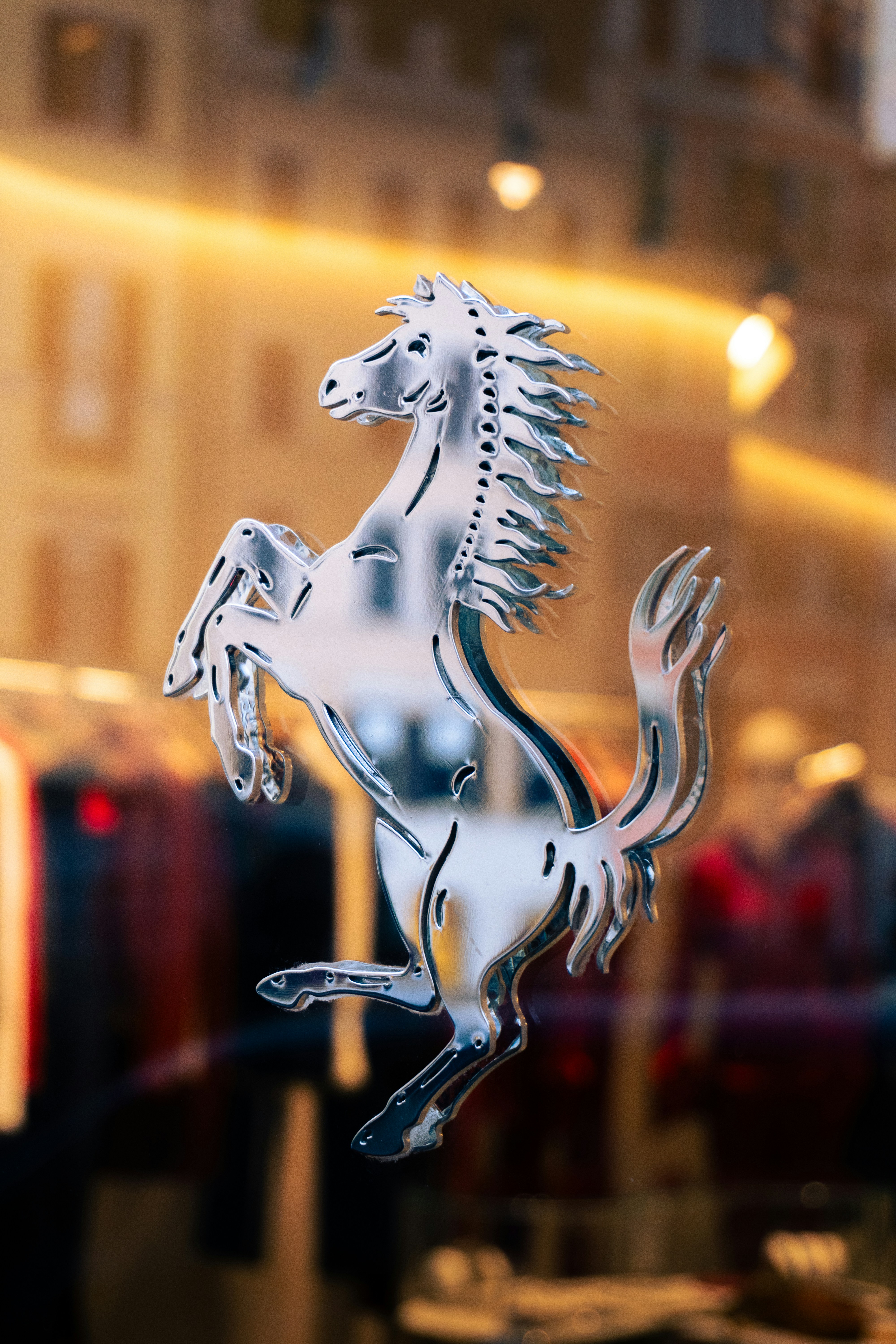 Silver prancing horse logo on blurred background