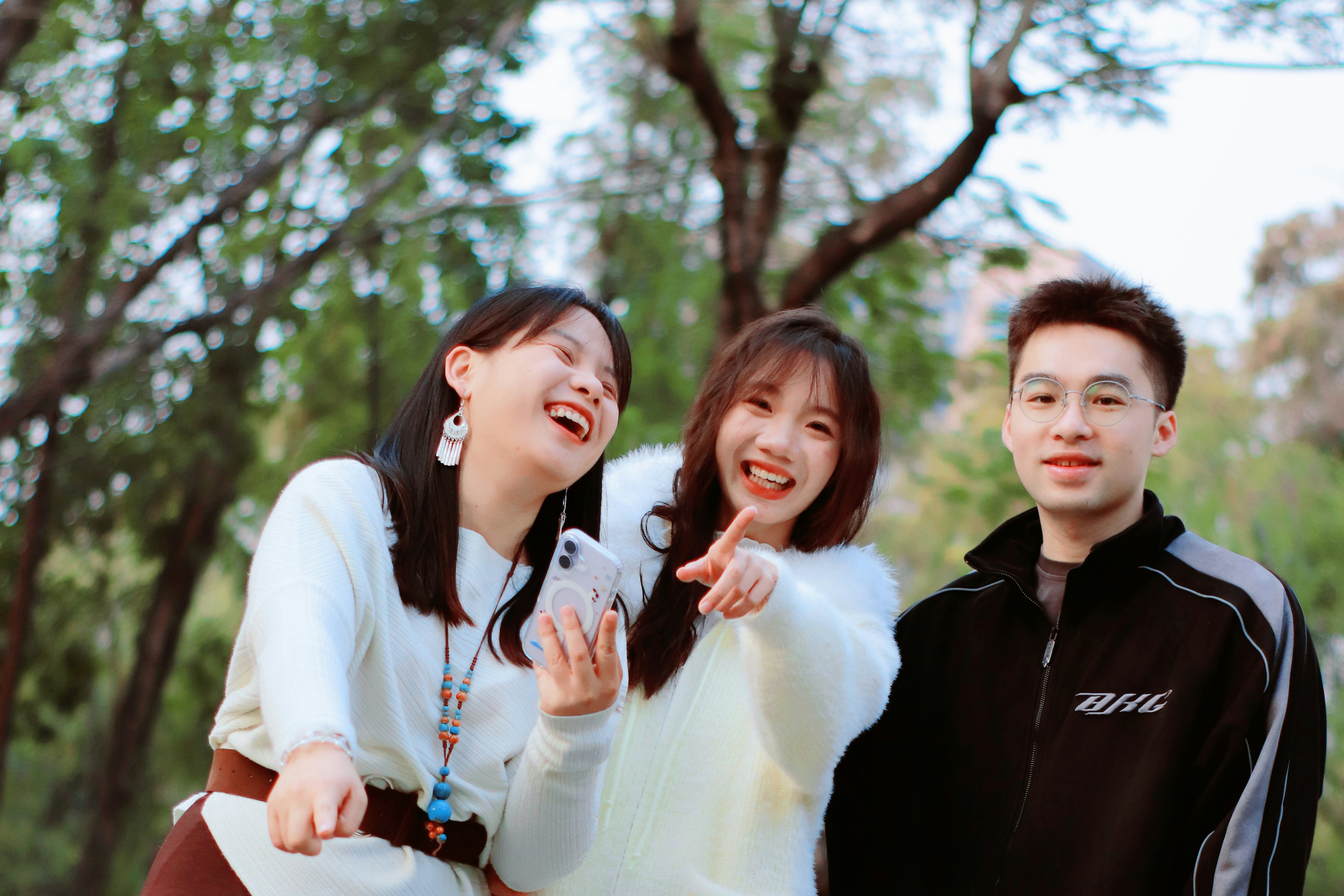 Three friends laughing and looking at a phone