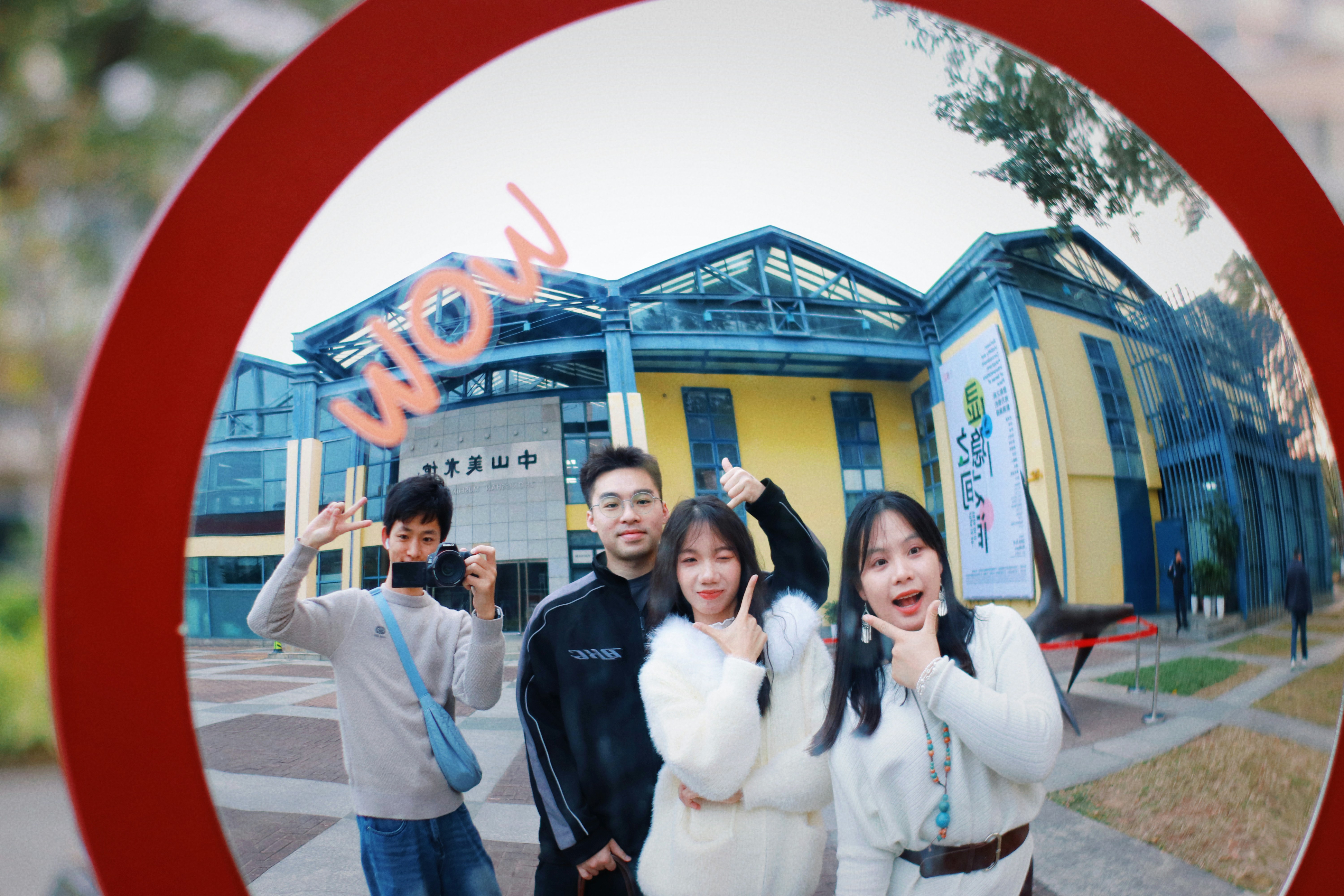Four friends pose in front of a modern building