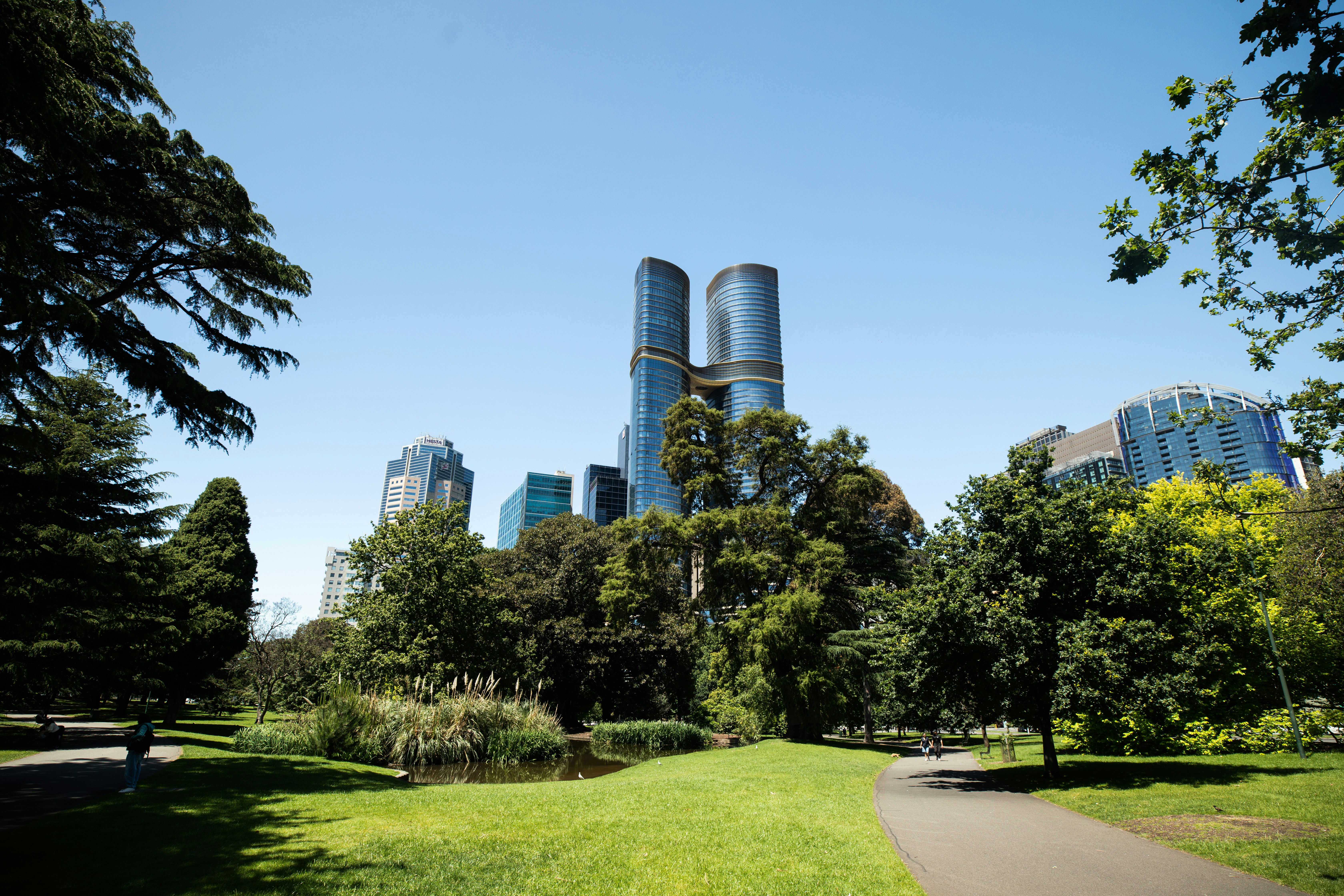 Modern skyscrapers rise above a lush green park.