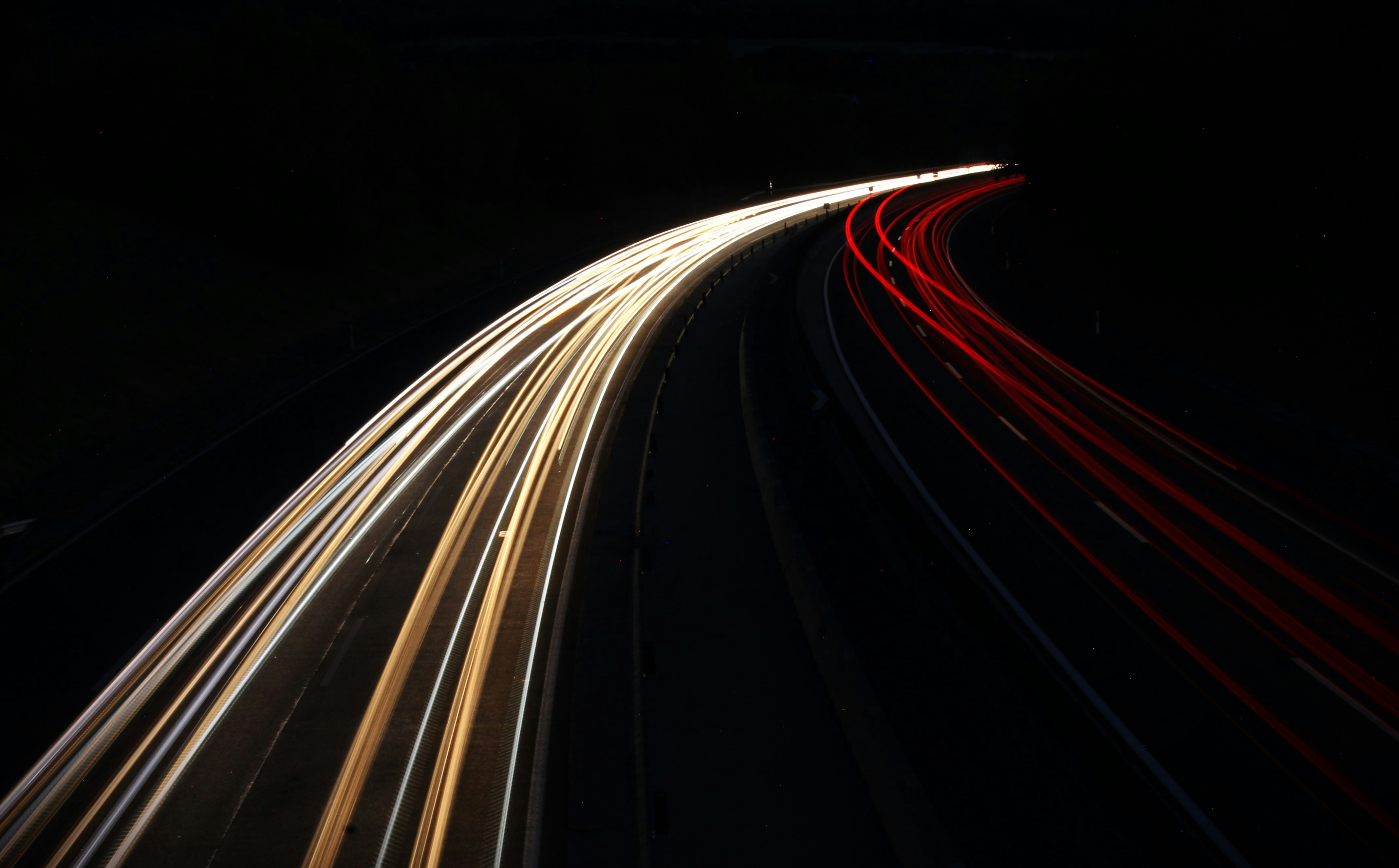 Light trails of cars on a dark road at night
