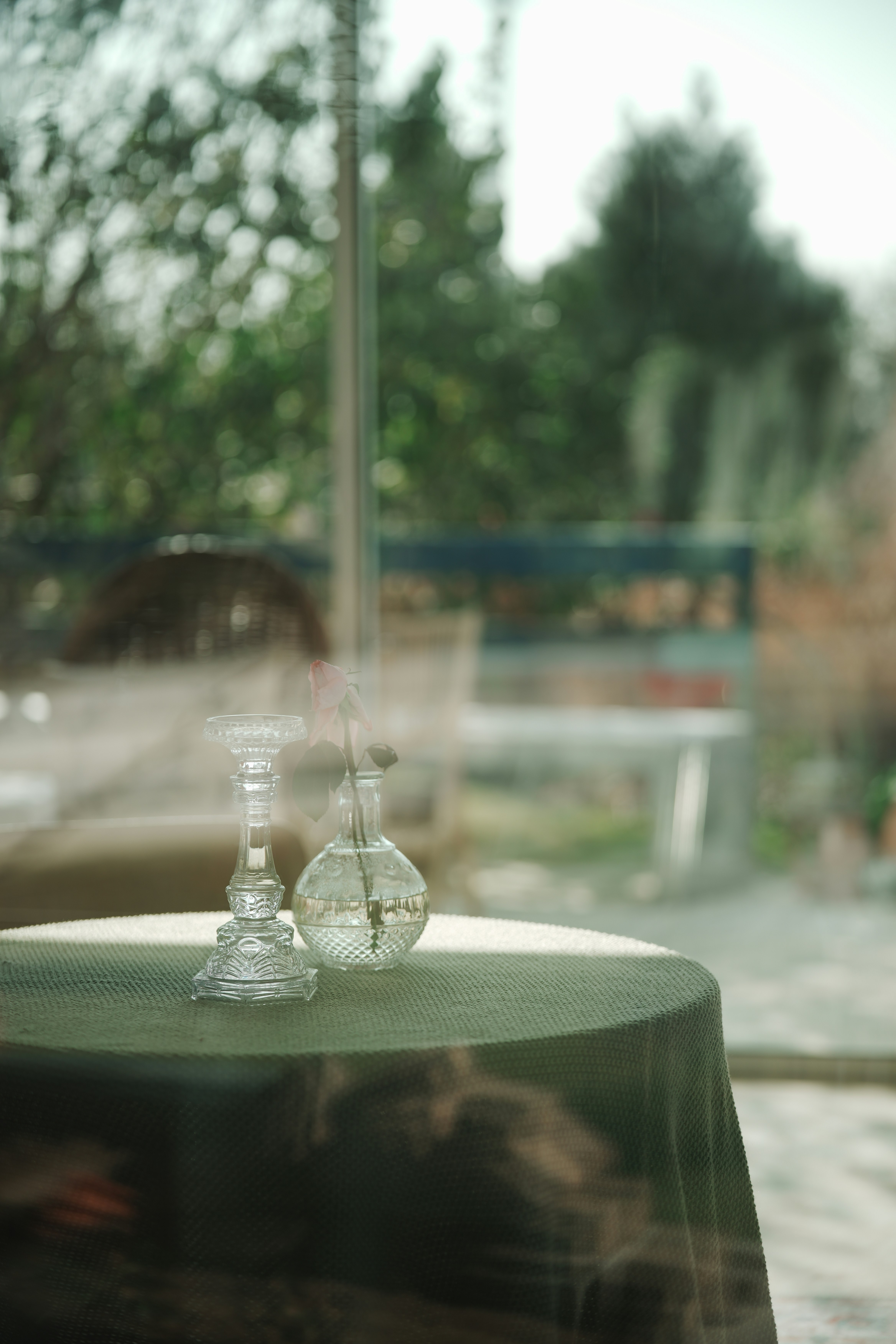Candlestick and vase on a table by the window.