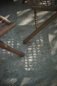 Wooden chair legs casting shadows on a textured surface.