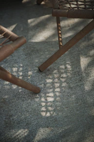 Wooden chair legs casting shadows on a textured surface.