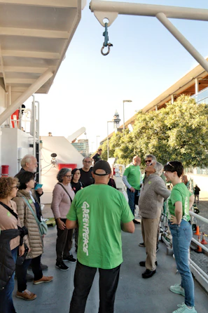 Greenpeace guide leads tour group on a ship deck.