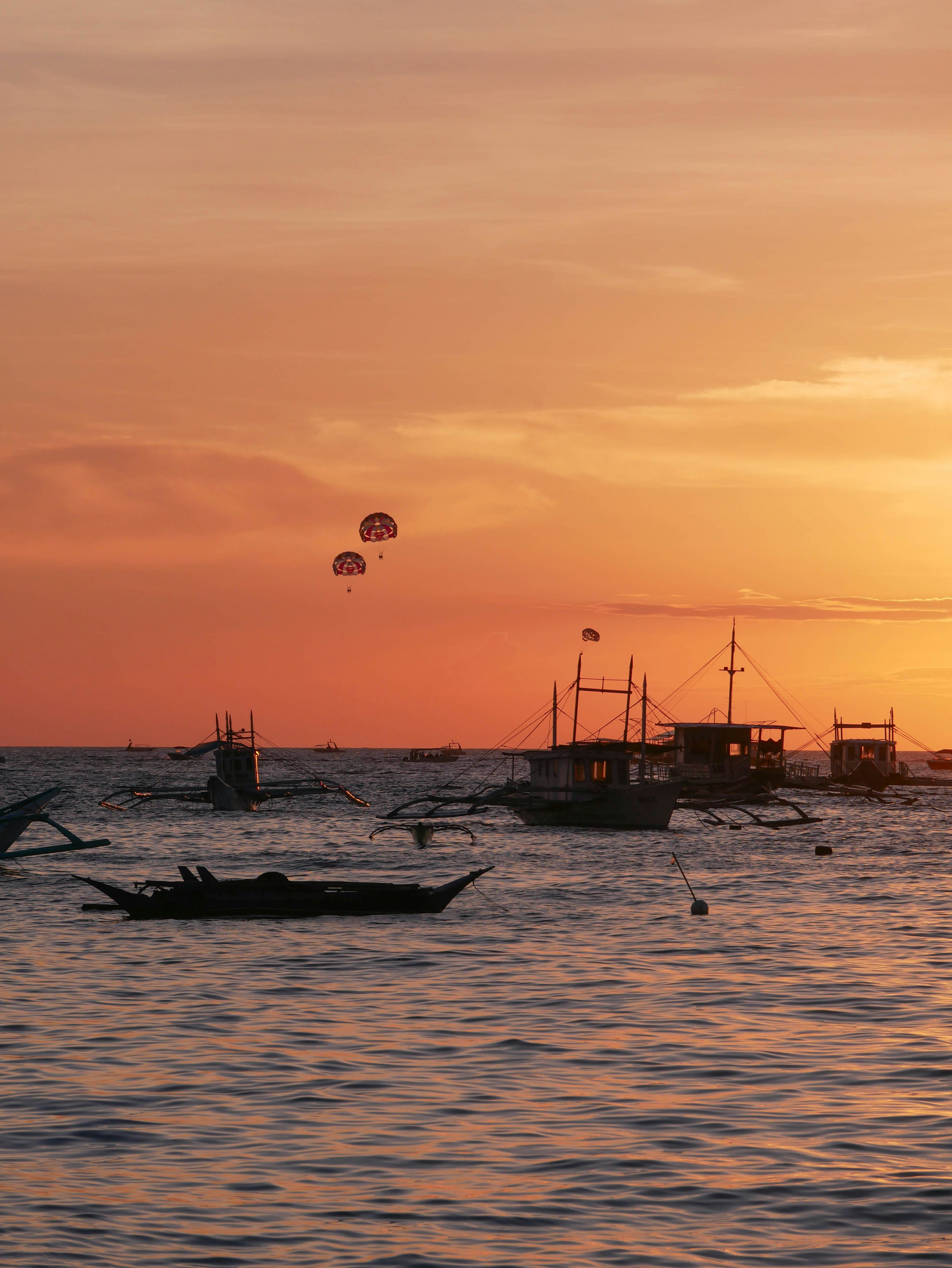 Barche sull'acqua con parapentisti al tramonto