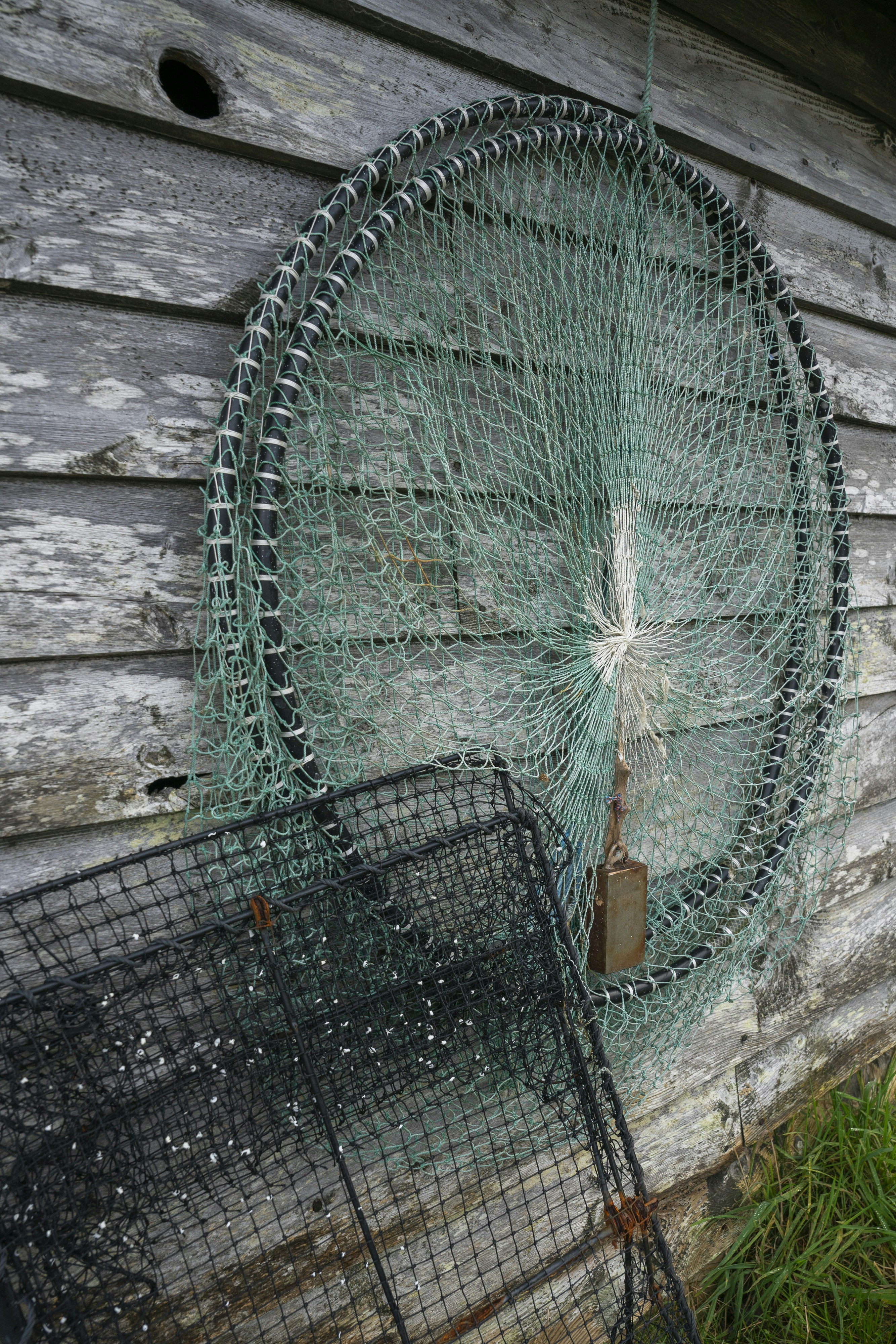 Fishing nets hang on a weathered wooden wall.