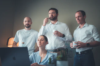 Four people in a room looking at a laptop.
