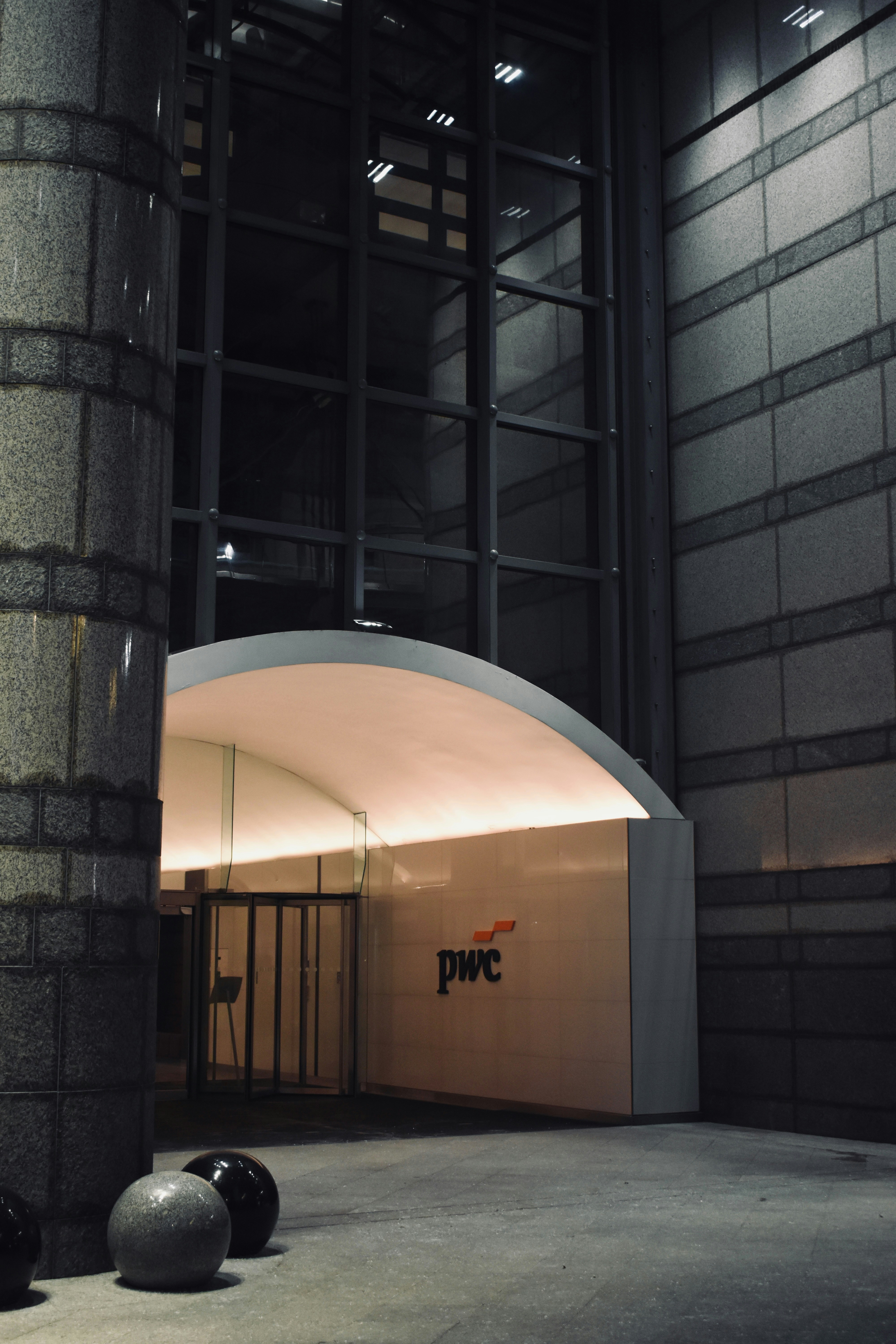 Moderner Gebäudeeingang mit PwC-Logo nachts