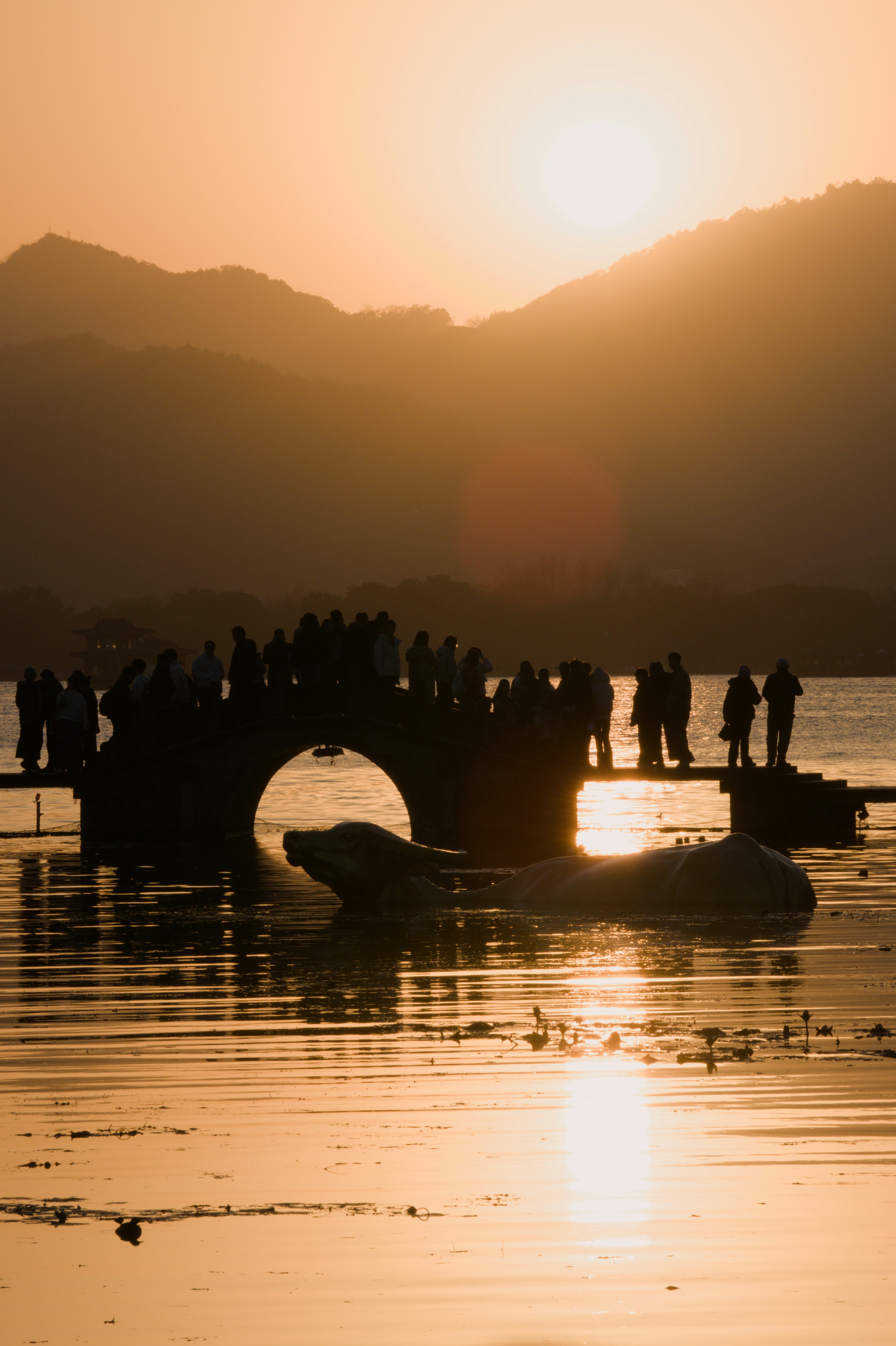 Gente en un puente al atardecer sobre el agua