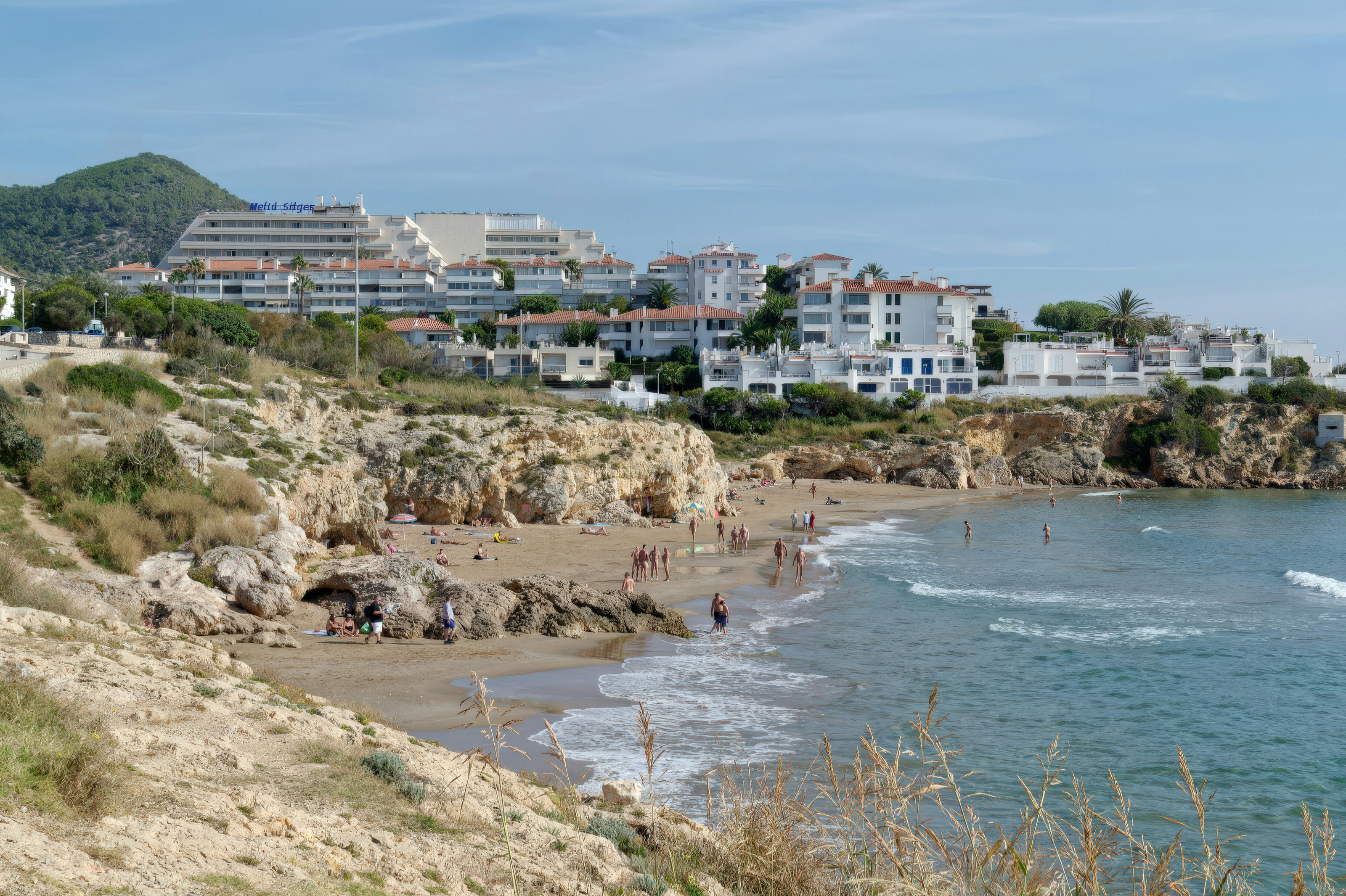 Coastal town with beach and buildings on hills.