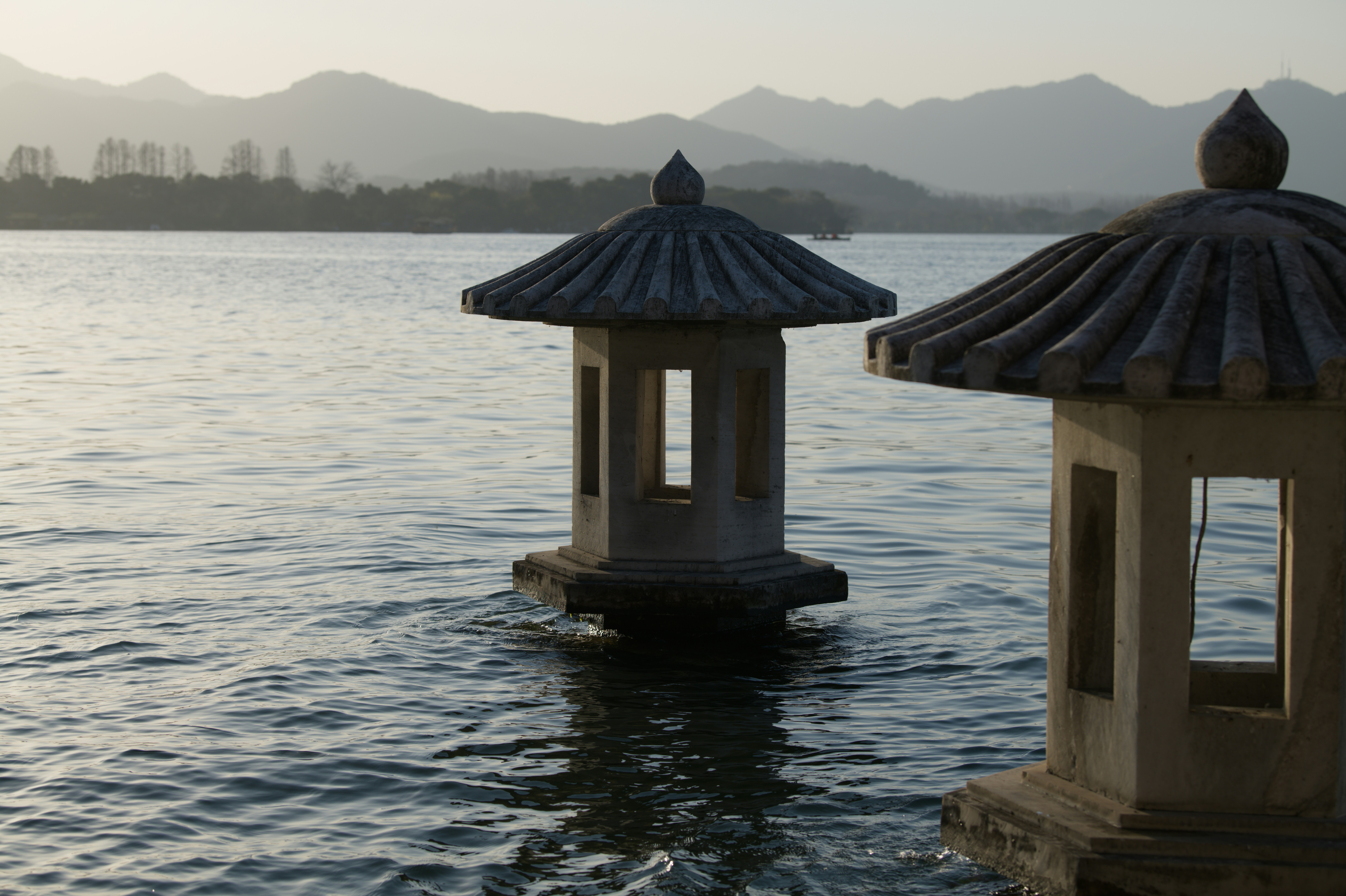 Dos farolillos de piedra en un lago tranquilo al anochecer.