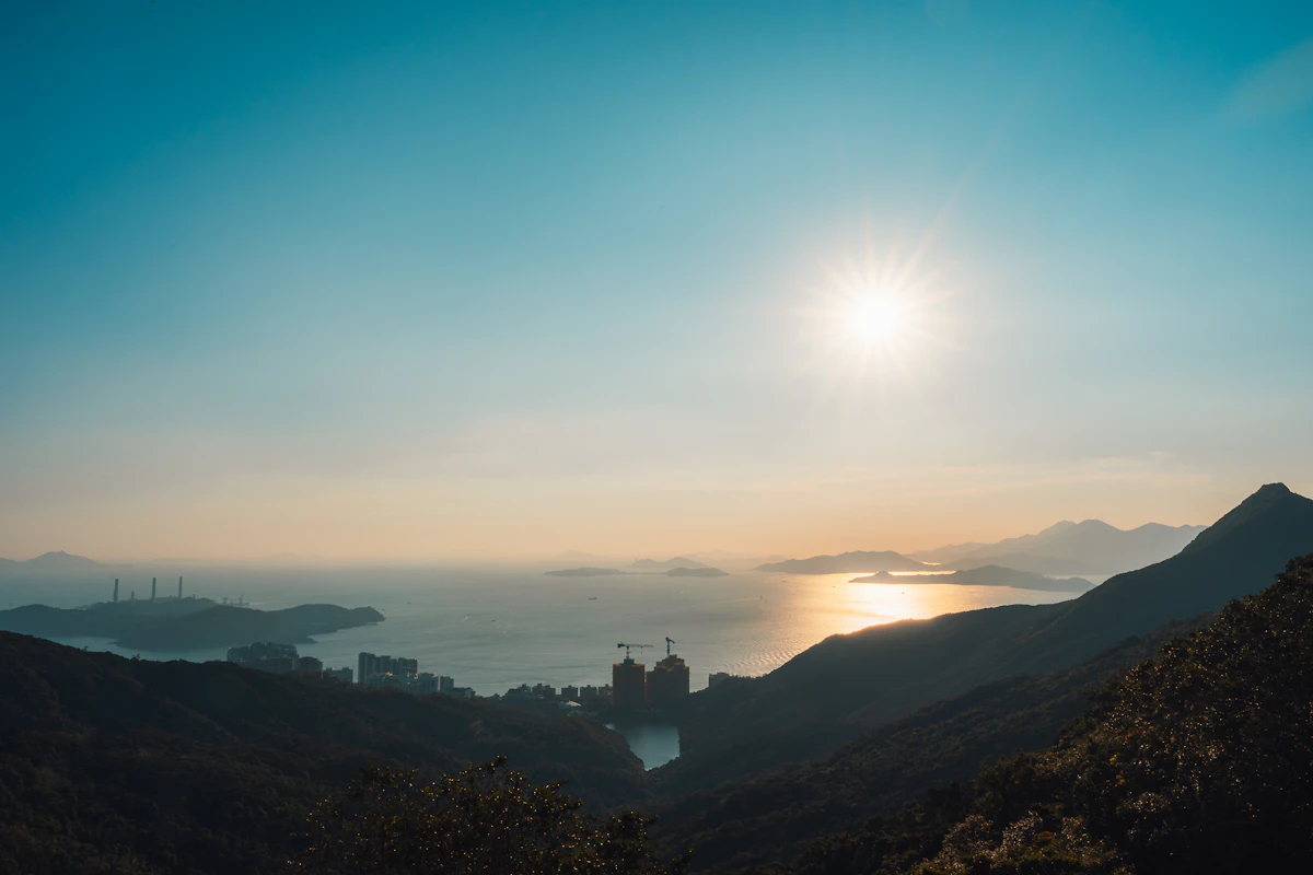 Sunset over the ocean with dramatic mountain silhouettes on the horizon