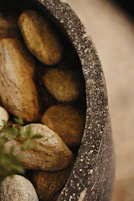 Smooth river stones fill a dark textured pot